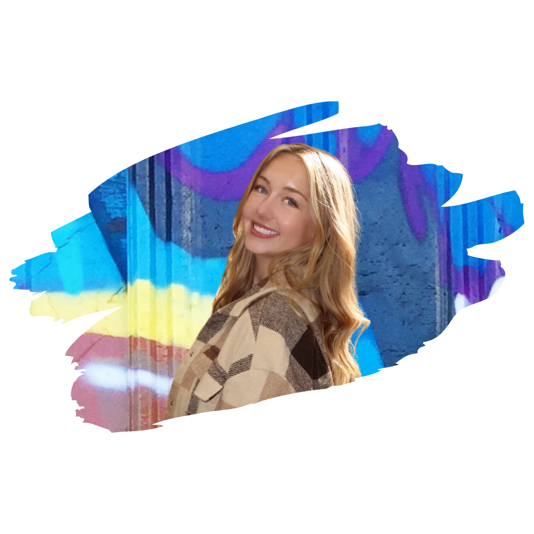 Image] Rachel Shropshire, therapist, smiling in front of colorful graffiti wall wearing a plaid jacket, Interfaith Bridge Counseling Denver Colorado team.