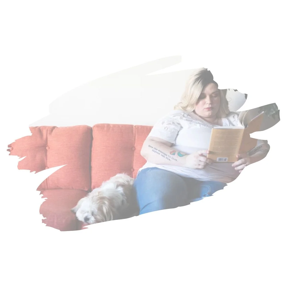 Young adult with tattoos relaxing on a couch reading a book with their dog, representing comfort and self-acceptance in neurodivergent-affirming therapy for teens and young adults in Colorado at Interfaith Bridge Counseling.