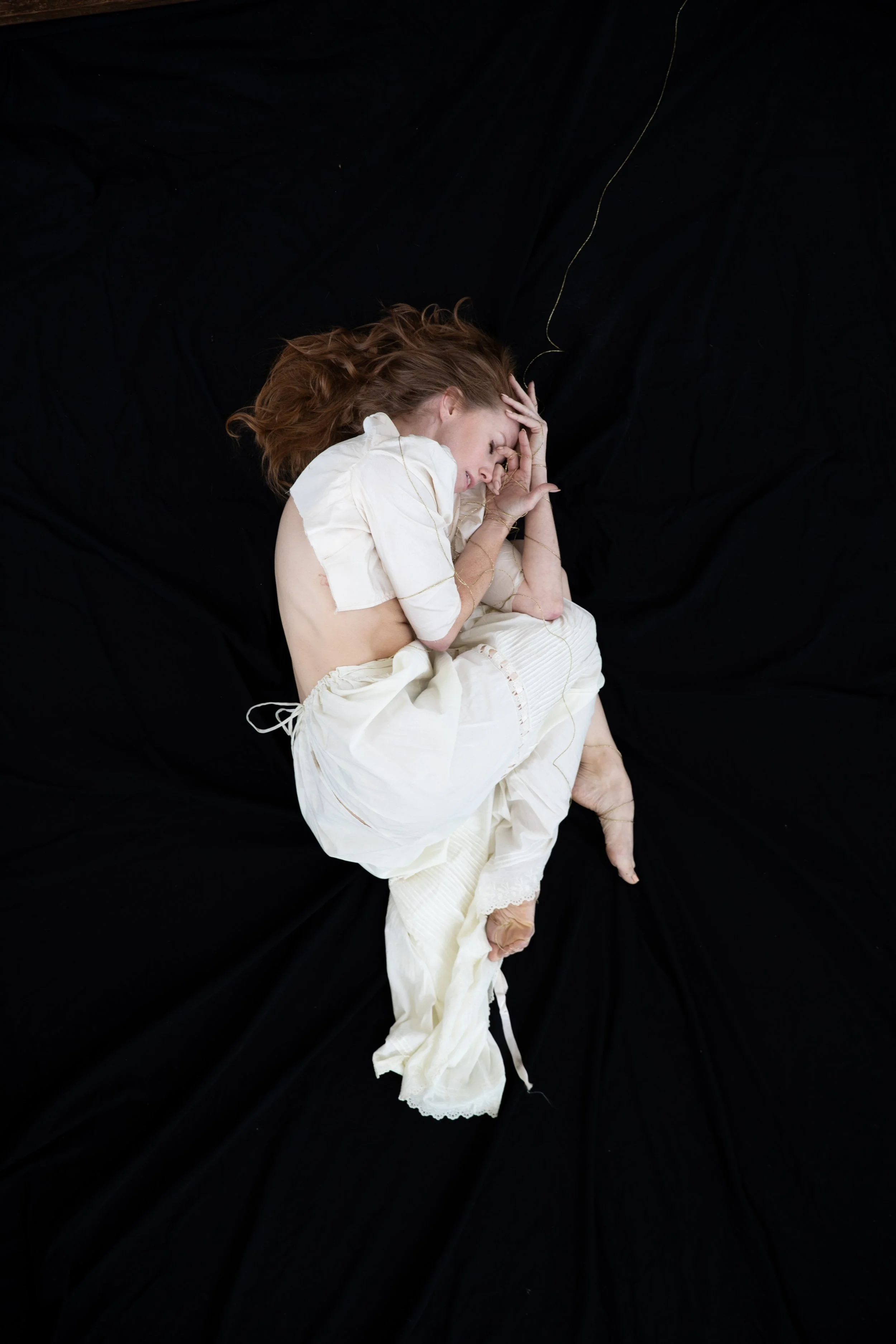 Woman in white curled into fetal position.
