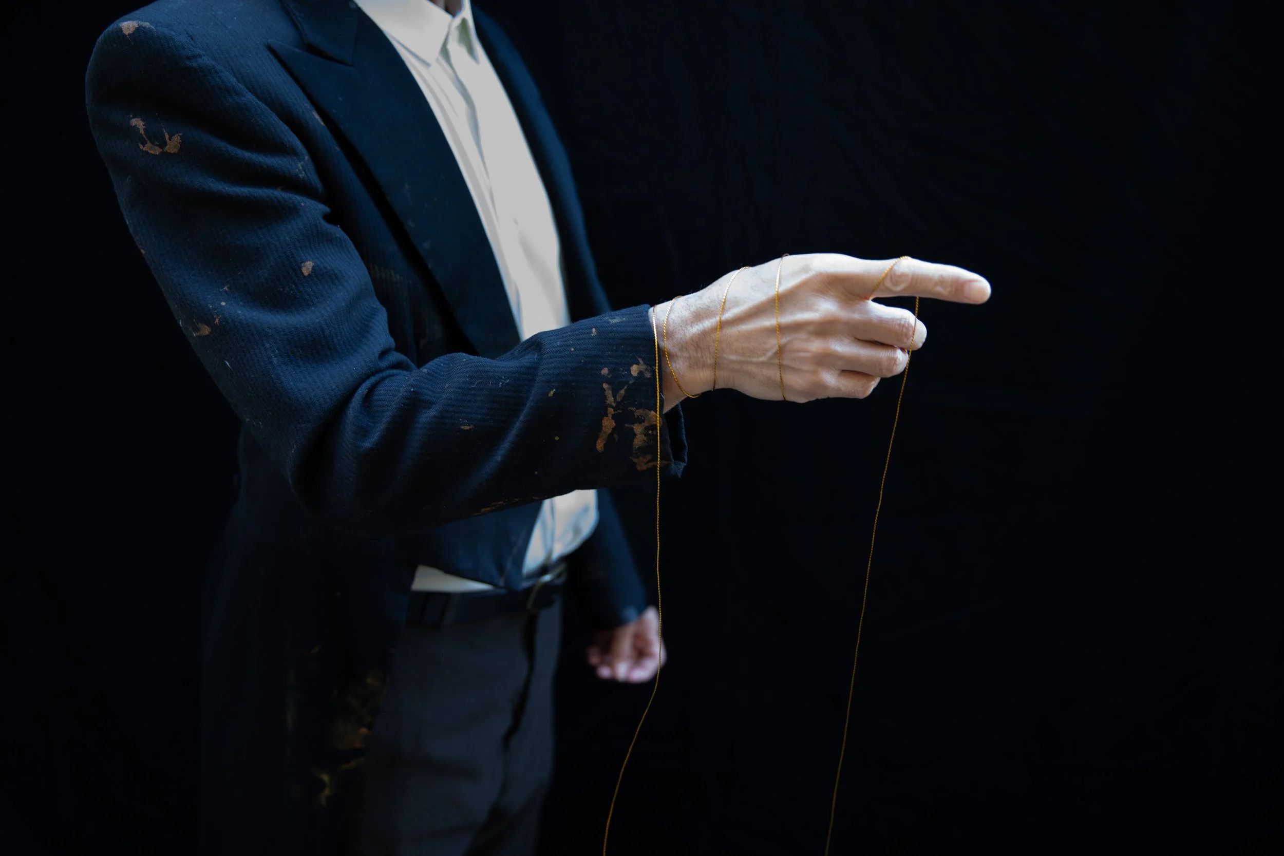 Man's hand with golden thread lightly tied around.