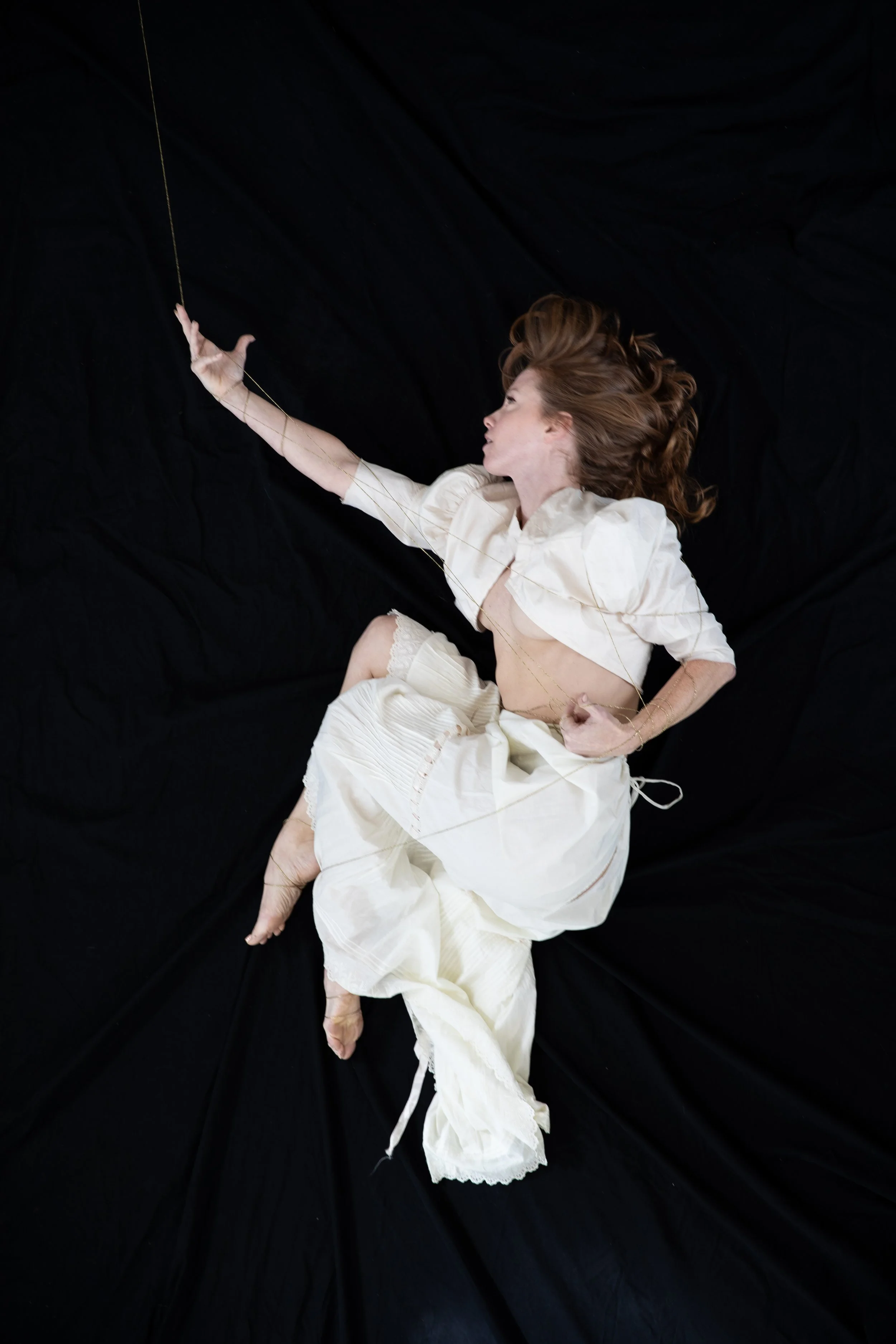 Woman in white now curls legs in toward her body, keeping her arm outstretched.