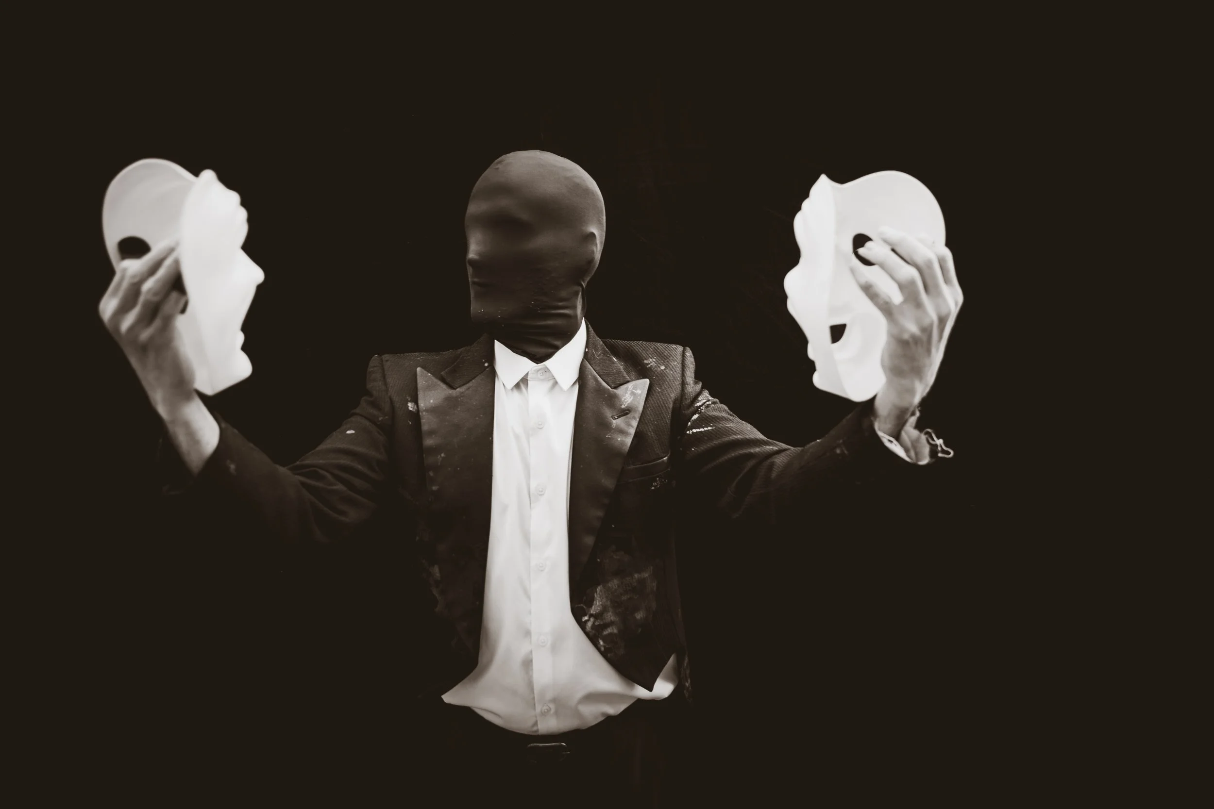 Faceless man holds both masks out as if he is close to choosing.