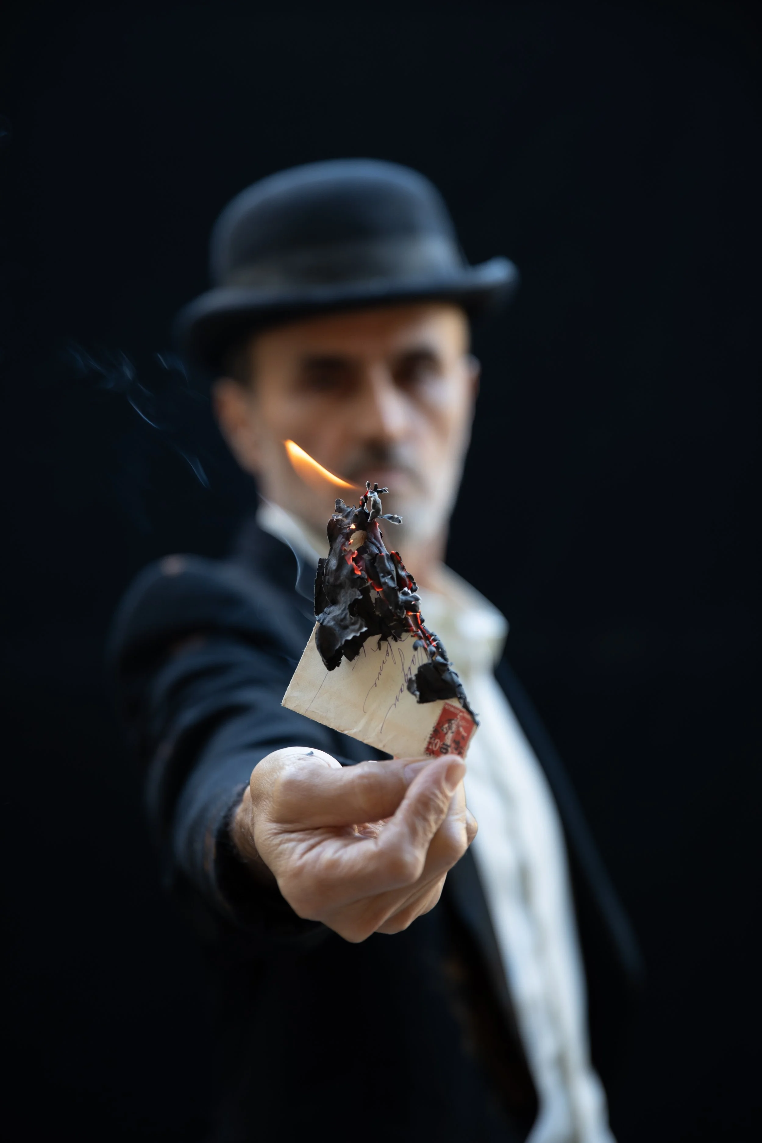 Man holding burned letter, almost totally ash.