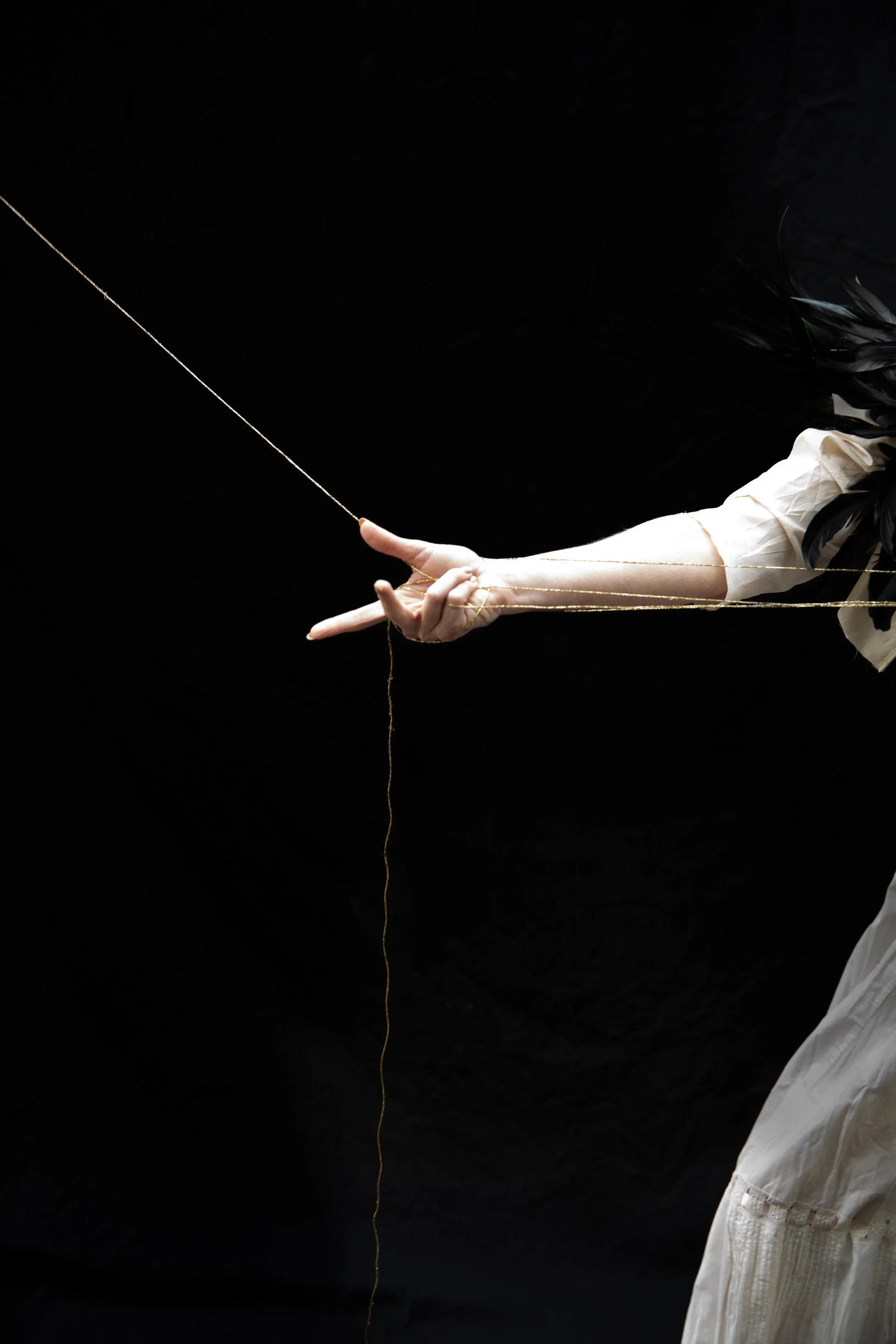 Woman's hand is holding the golden thread at an angle, with intent.