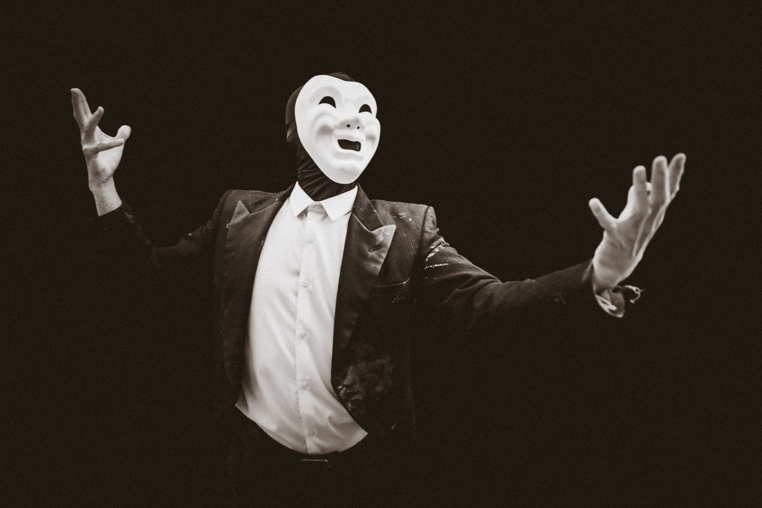 Man in drama mask looking up and holding hands out.