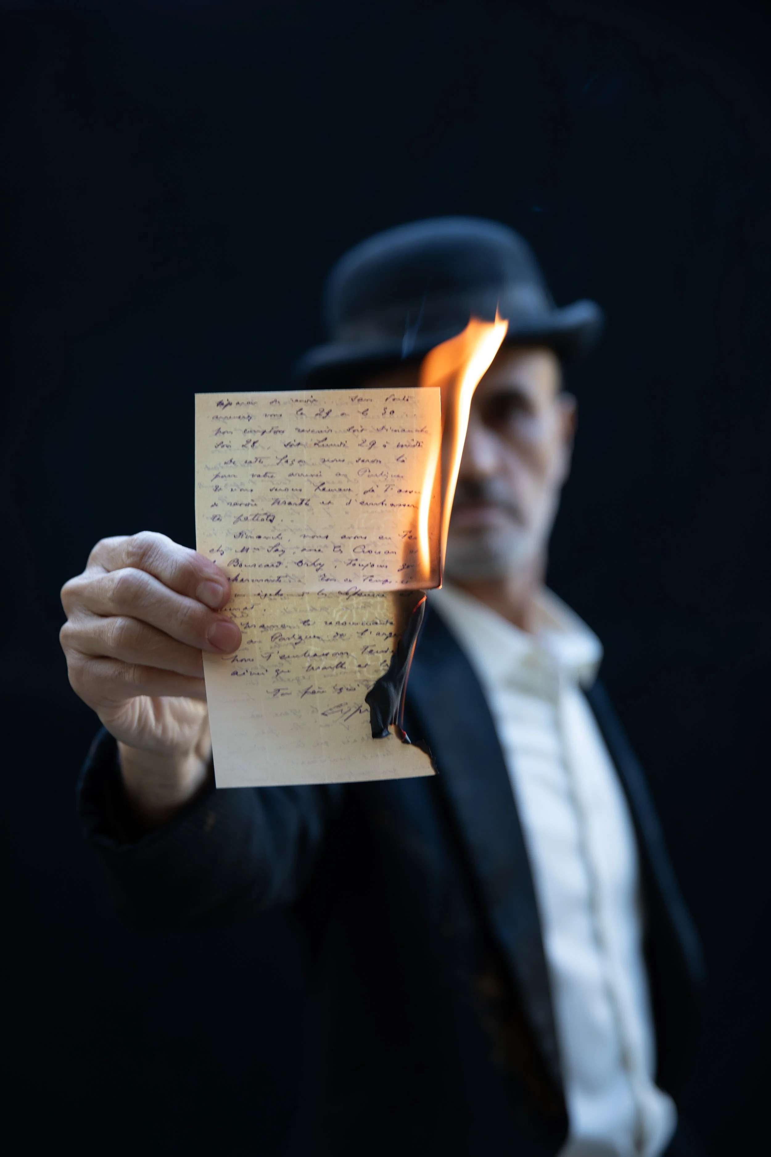 Man holds up a burning letter to the camera