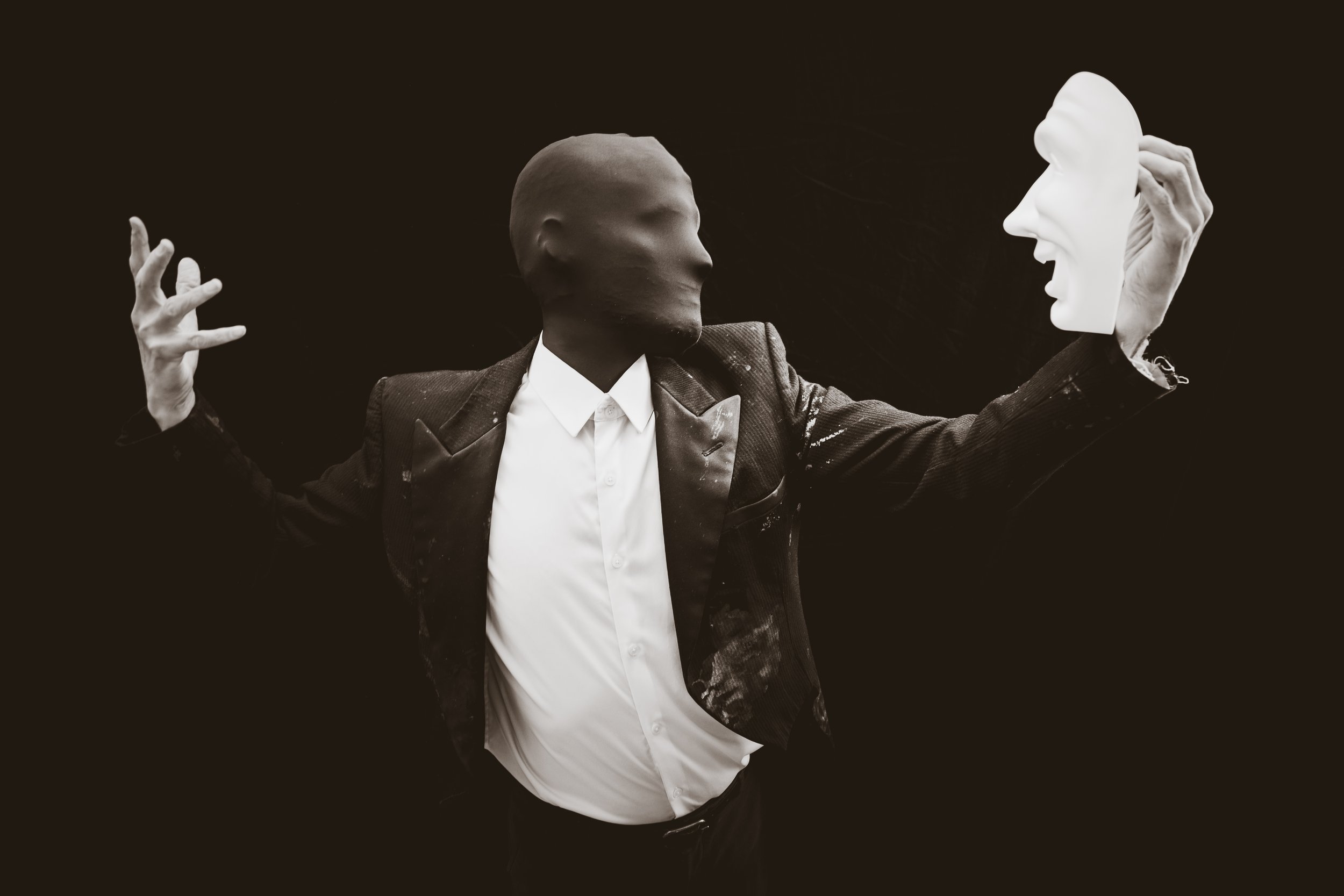 Faceless man holds out mask as if he's chosen it.
