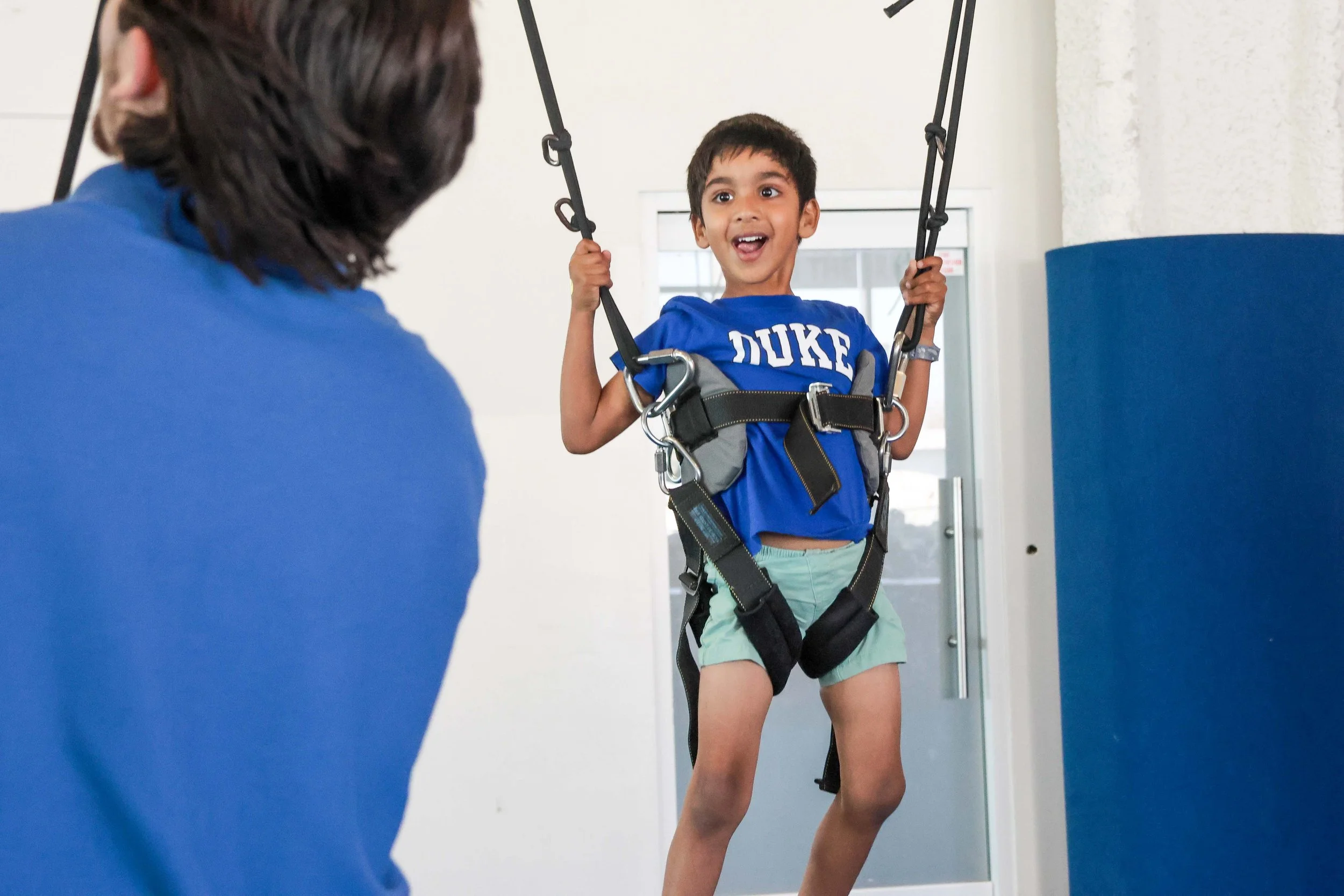 Young girl jumping on a trampoline at an indoor kids' play area, smiling and having fun