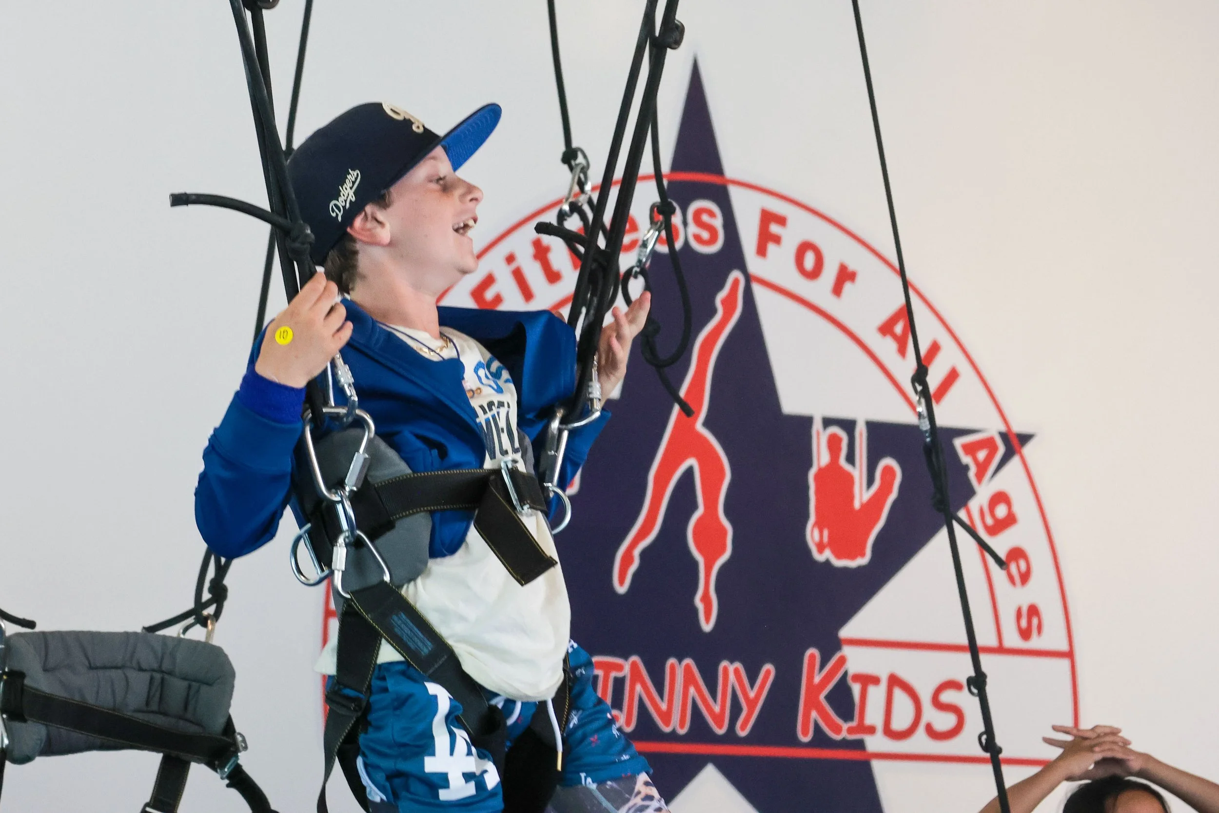 Young boy midair on a trampoline being assisted by an instructor at an indoor trampoline park.