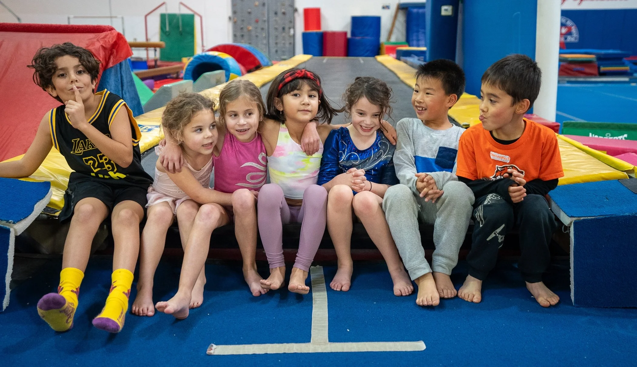 Young boy midair on a trampoline being assisted by an instructor at an indoor trampoline park.