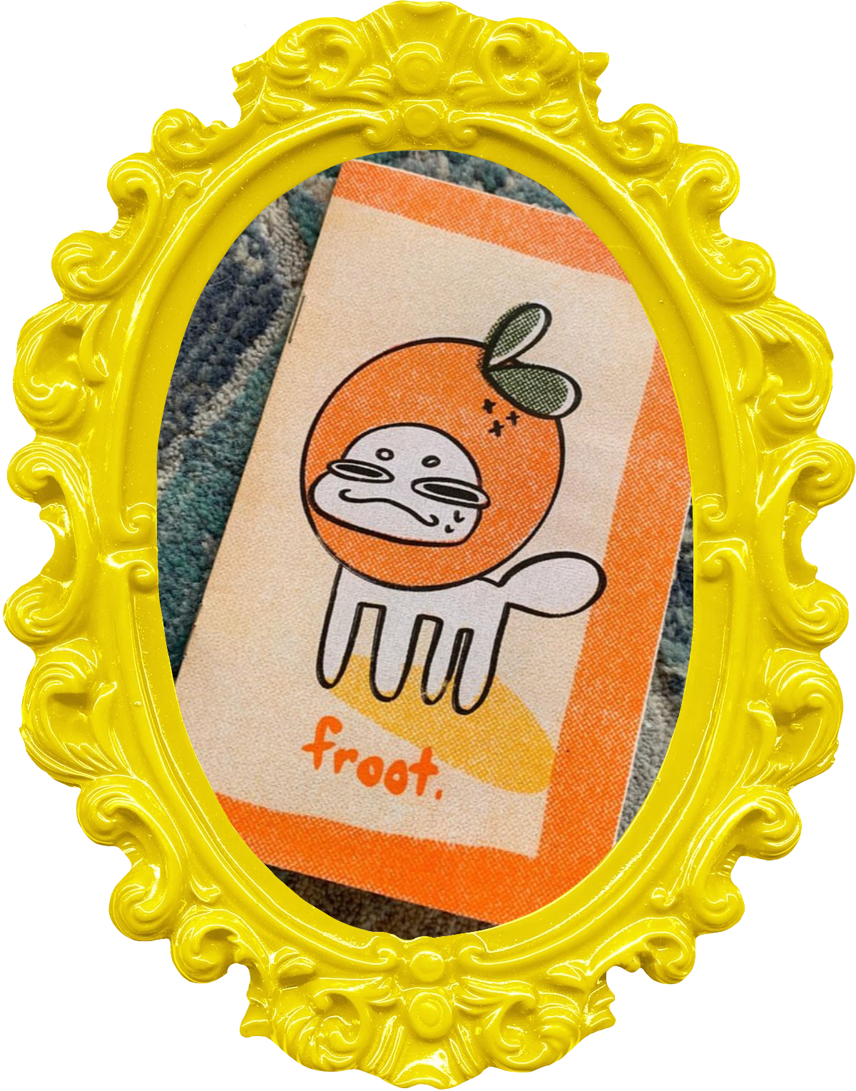 A zine with an illustration of a cat wearing an orange on its head on the cover. He has a mischievous expression and the zine title, "froot" written beneath him. The image is in a yellow frame.