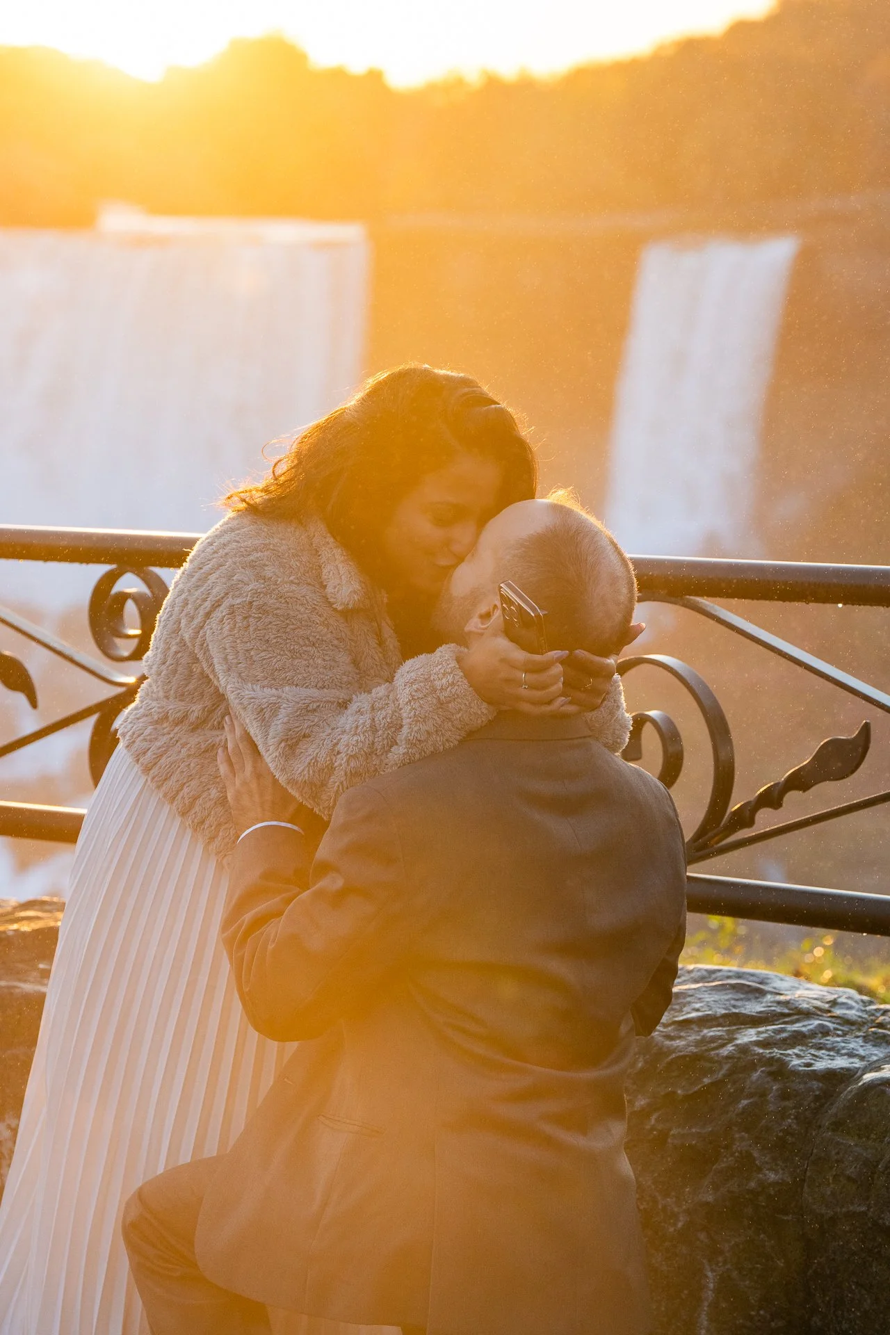 man and woman kissing after she accepts his marriage proposal at sunrise overlooking Niagara Falls