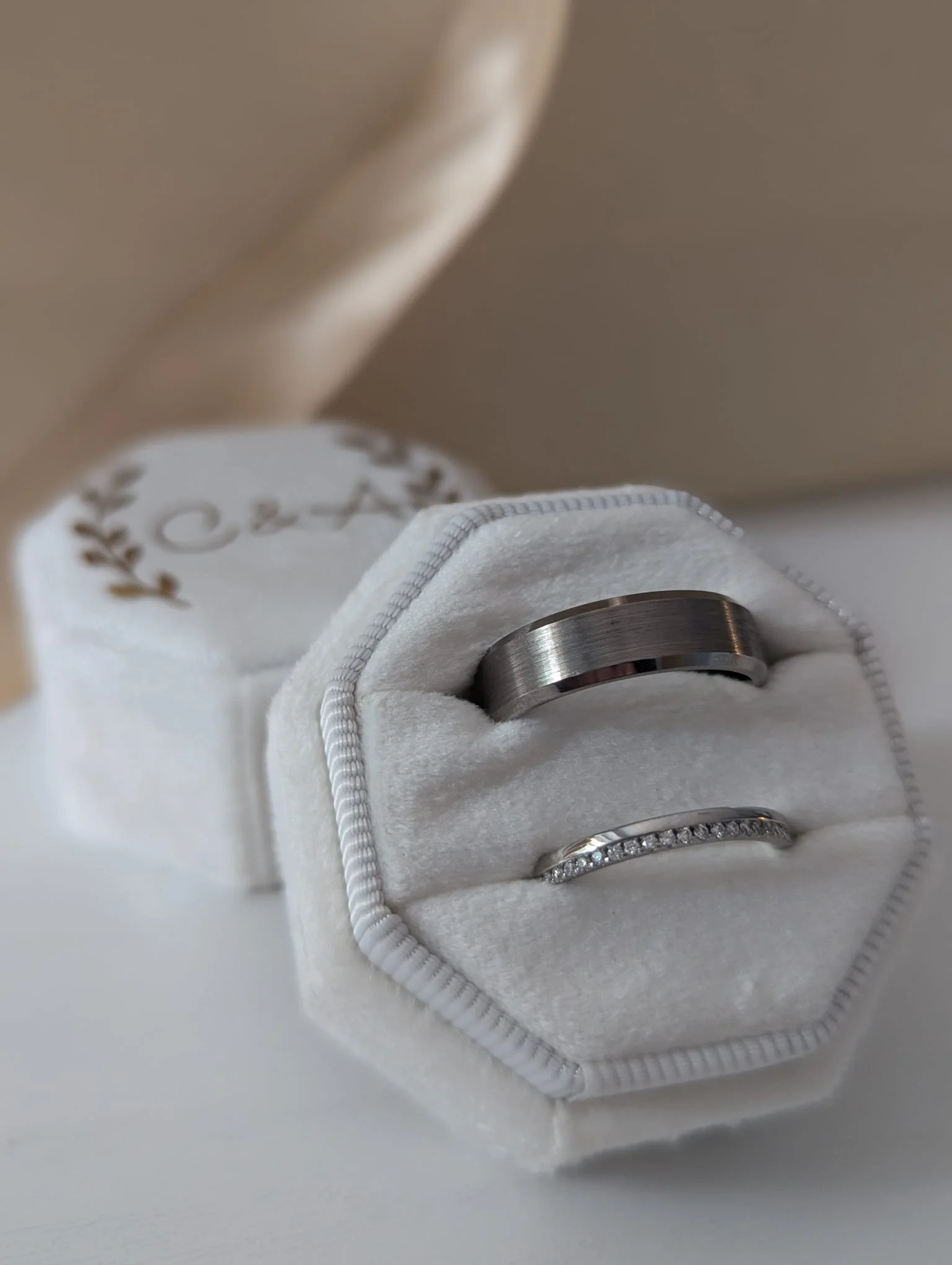 Silver wedding rings in a white velvet ring box.