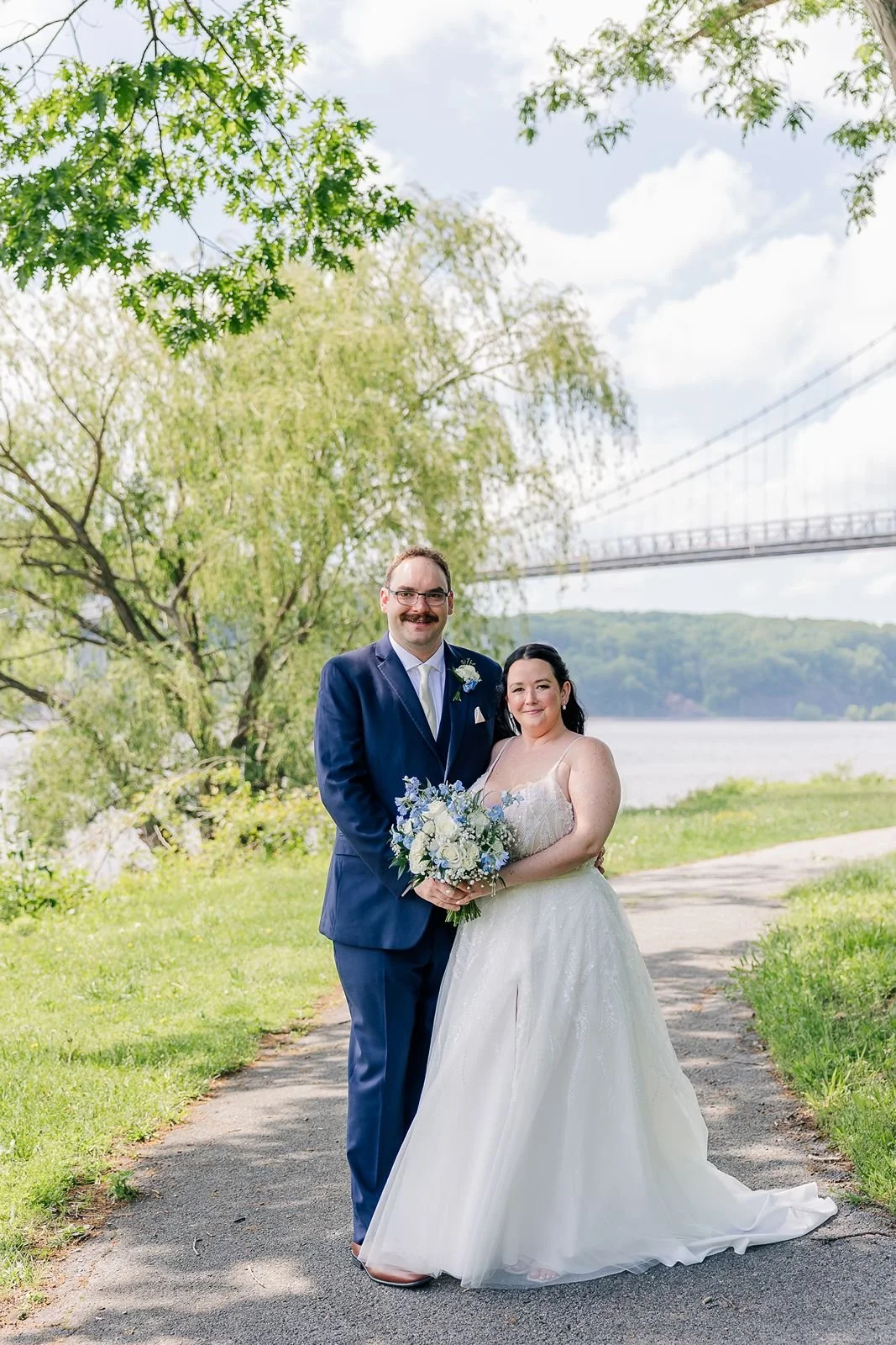 Bride and Groom standing along Hudson River waterfront by Mid Hudson Bridge
