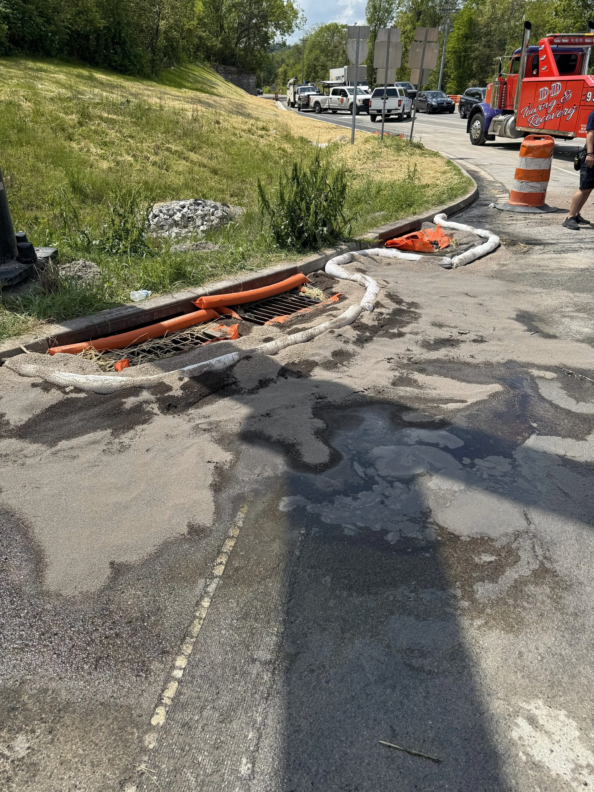 Immediate containment operations following a transportation-related fuel release. Storm drains were protected using drain covers, absorbent booms, and recovery materials to prevent contamination from reaching nearby drainage systems and surface water
