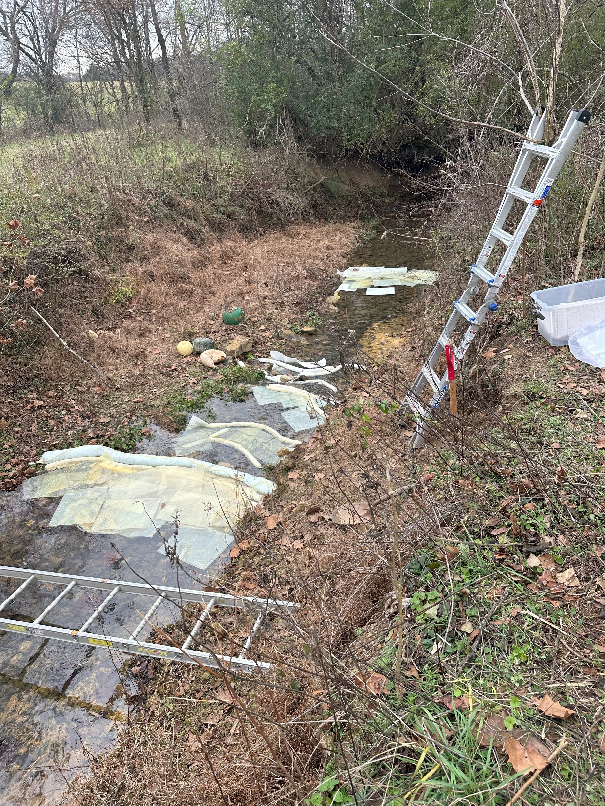 Environmental response operations supporting containment and recovery efforts within an impacted creek following a petroleum release. Absorbent booms and pads were strategically deployed to capture contamination, protect downstream waterways, and sup