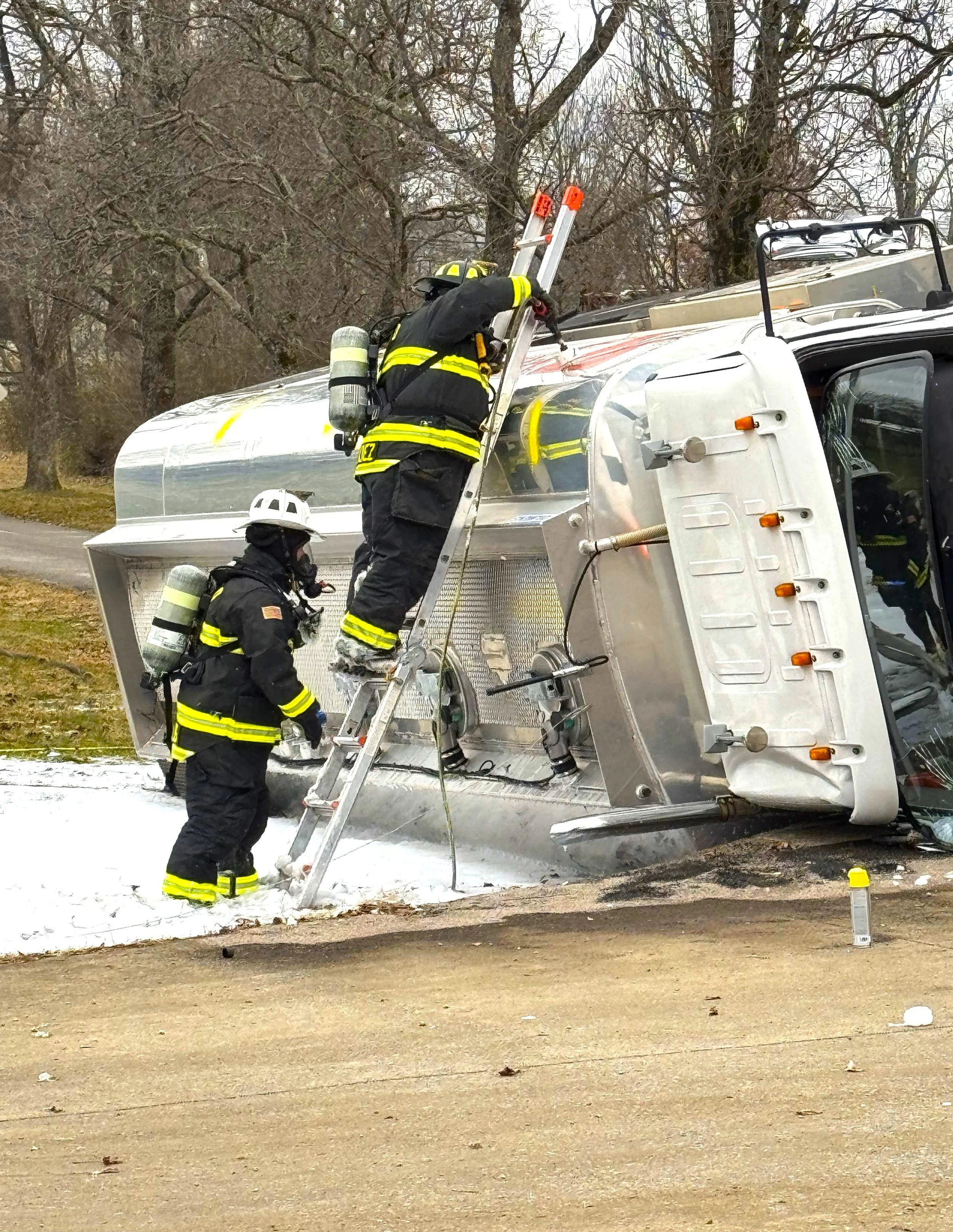 Emergency response team working on an overturned tanker truck during a hazardous materials incident.