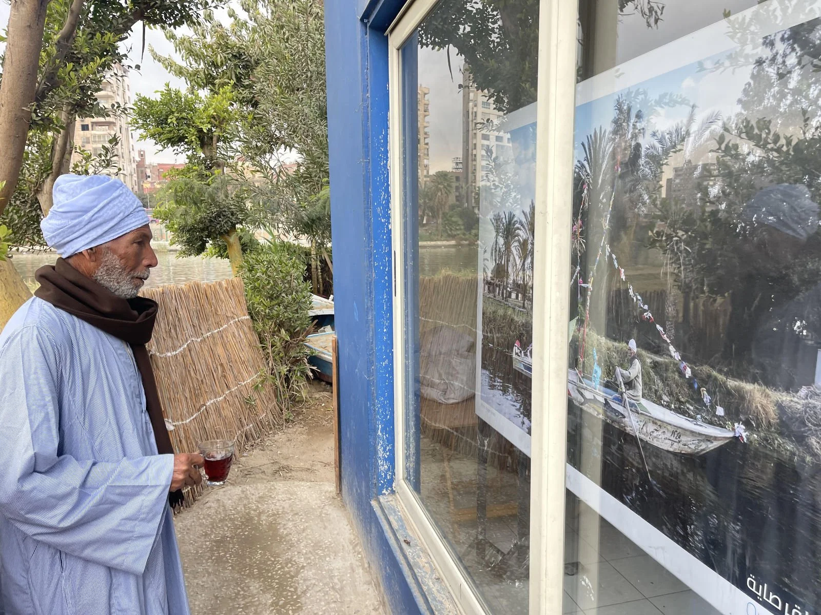 Abo Sayed seeing a large print of himself with his granddaughter from the last Nile Parade in 2024. Standing in front of it and inviting his daughter and granddaughter with so much pride to look at it.