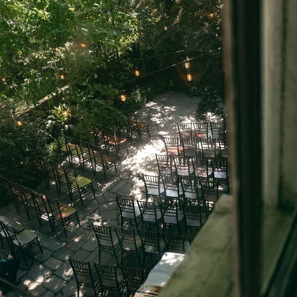 There&rsquo;s a quiet kind of magic in the moments before a ceremony begins. 🌿✨ Chairs stand ready beneath a canopy of trees, light filters through the leaves, and the soft glow of string lights hints at the celebration to come.

For me, this is one