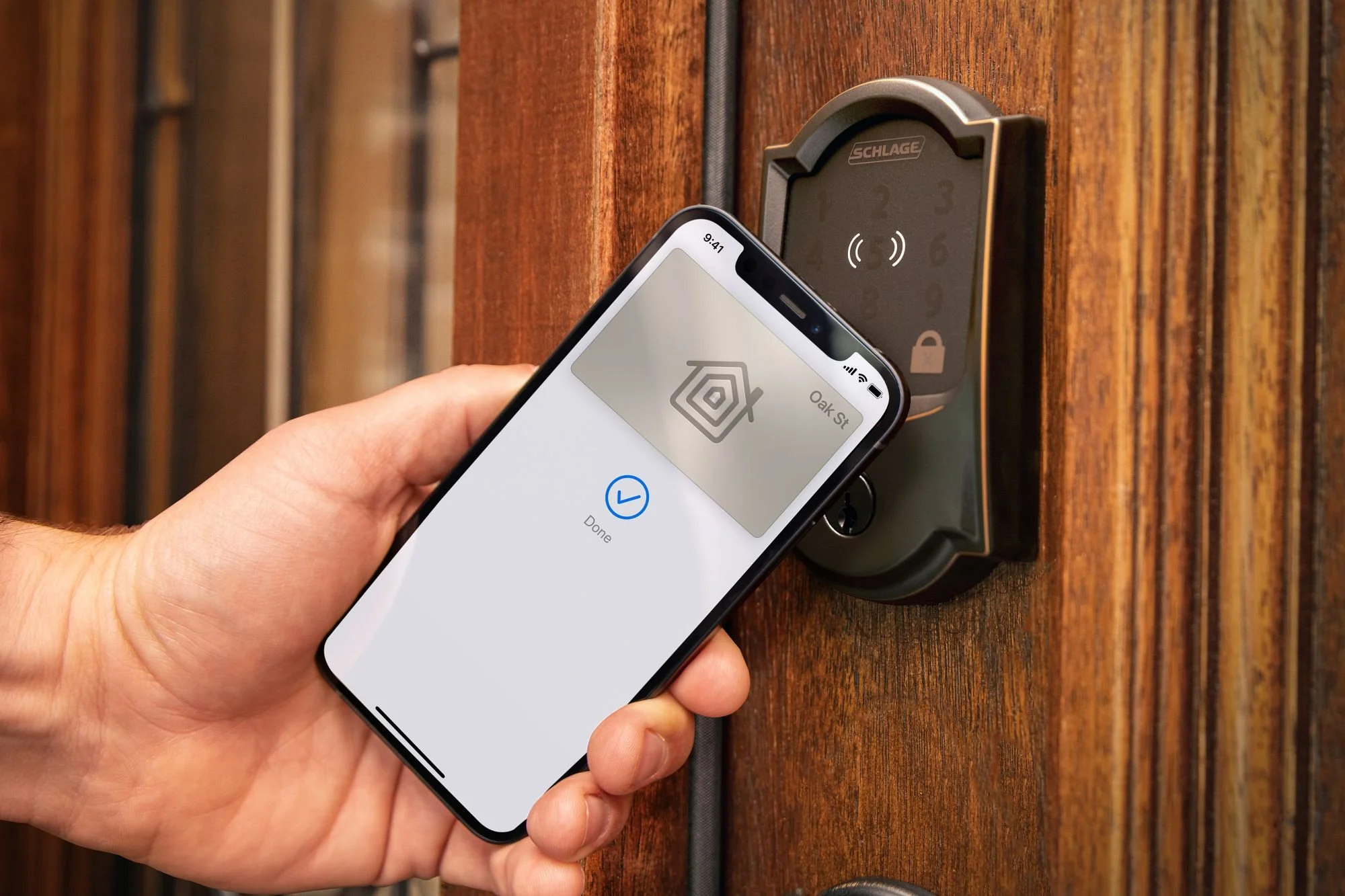 Person using a smartphone with a digital lock on a wooden door.
