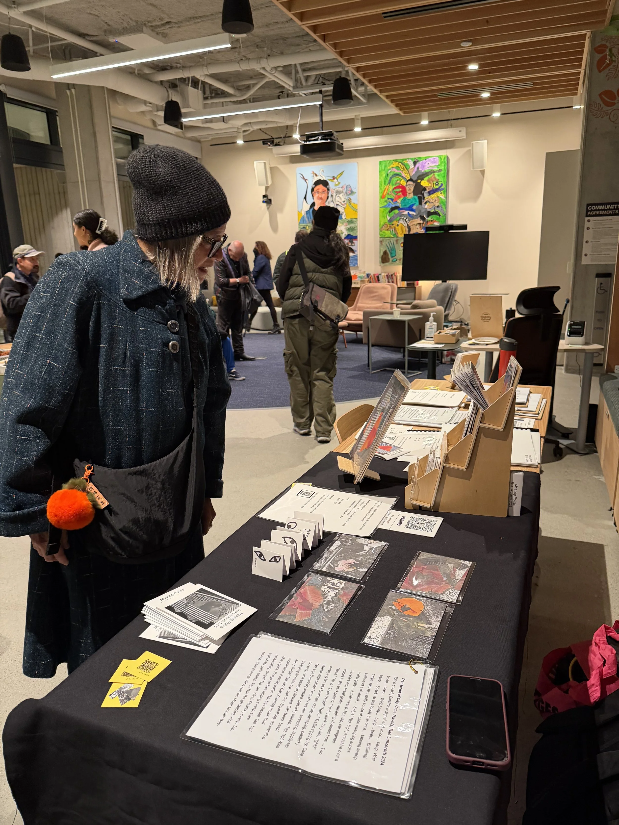 Visitor to Meeting Points at the SF Disability Cultural Center stands by table with zines and tactile prints and Exhibit Guide.