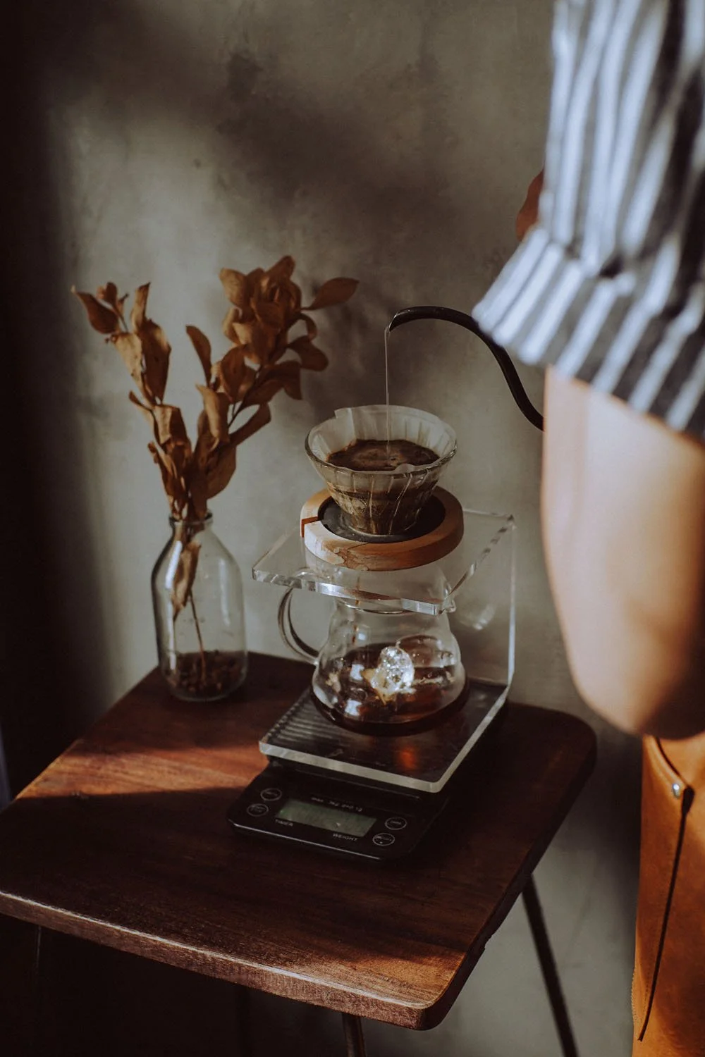 woman pouring hot water into coffee pour over on table