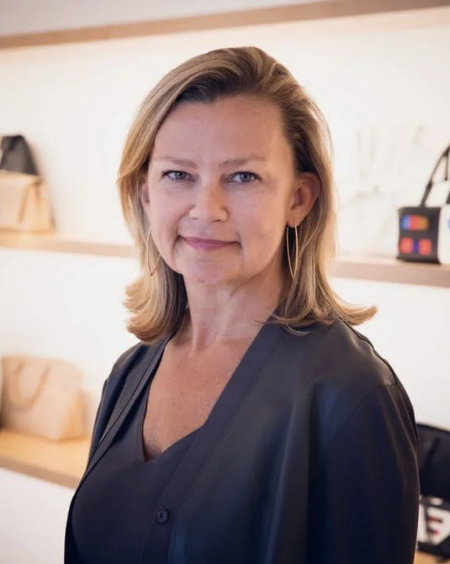 Woman standing at a podium in a classroom or conference room, speaking.