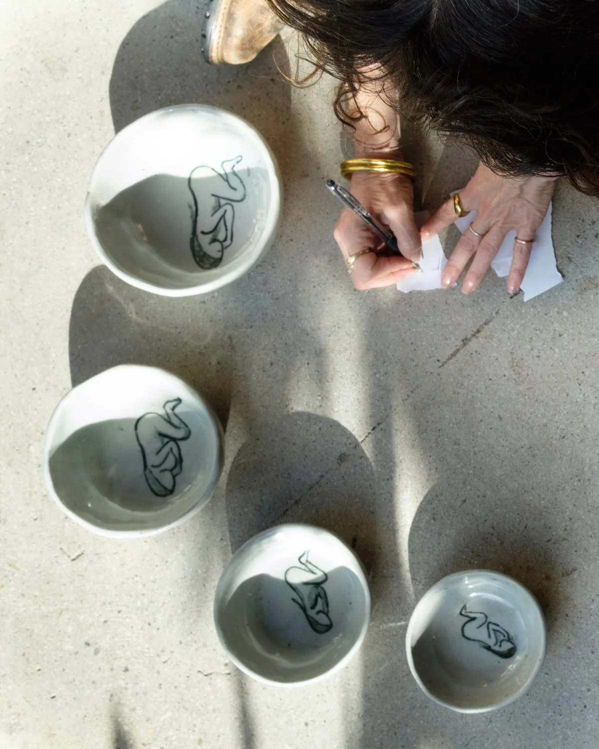 Handmade ceramic bowls painted with a resting woman, seen from above