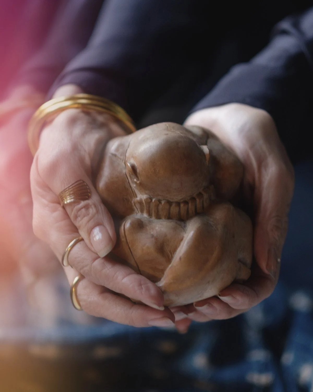 Cupped hands holding a small hand-carved wooden figure