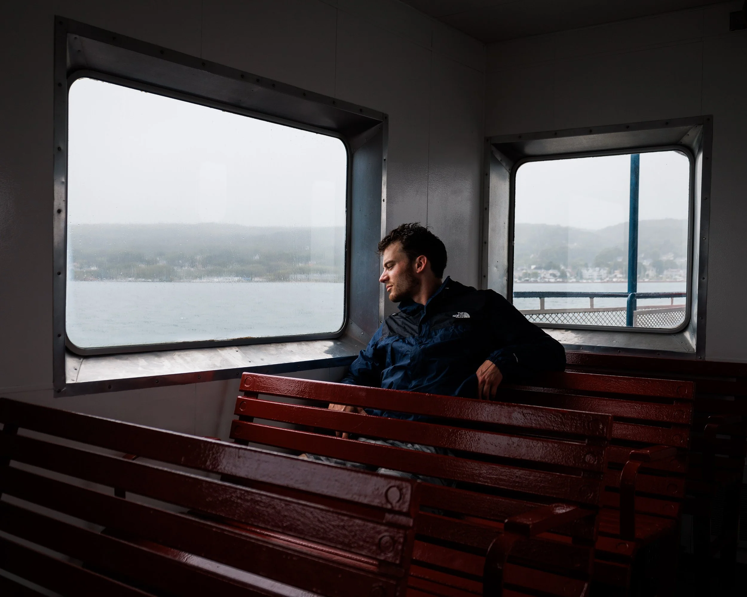 Man looking out ferry window on gloomy day near Bayfield Wisconsin going to Madeline Island
