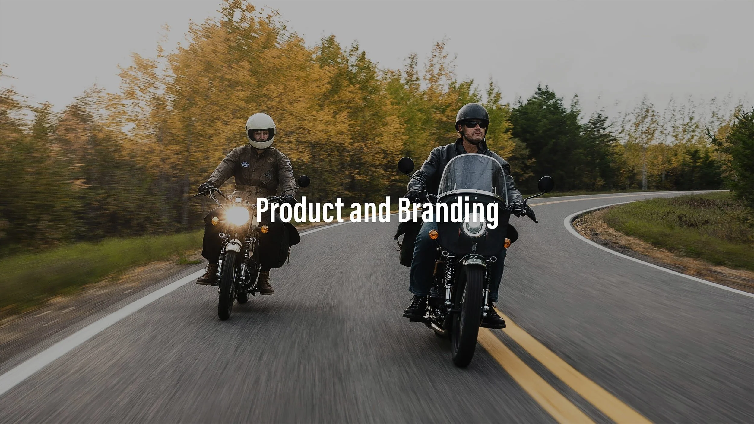 Two motorcyclists riding on a winding road surrounded by trees with fall foliage, one with a tall windshield and the other with a helmet and sunglasses, with the text 'Product and Branding' overlayed.