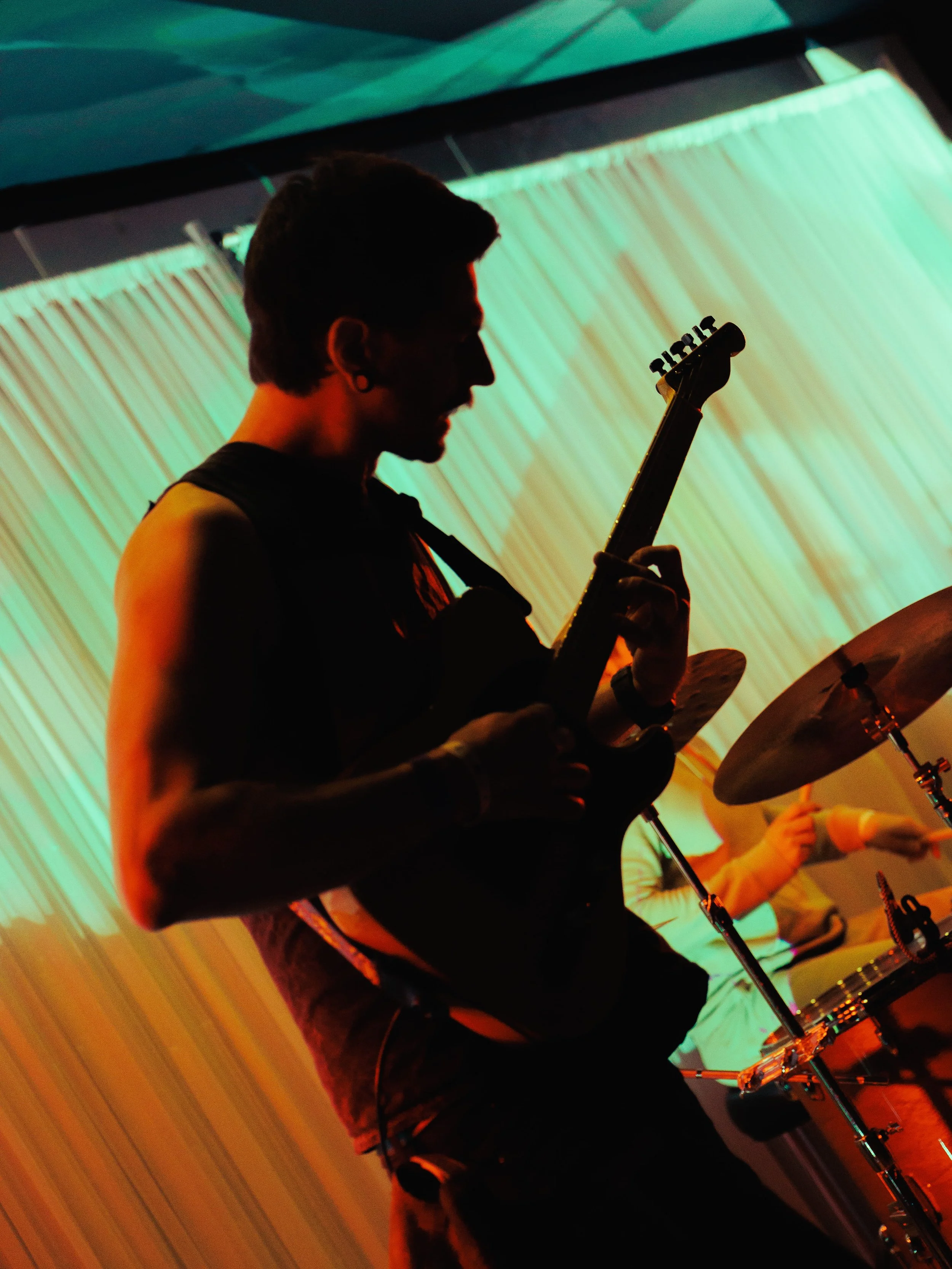 A person playing drums in a dark room with colorful lighting.
