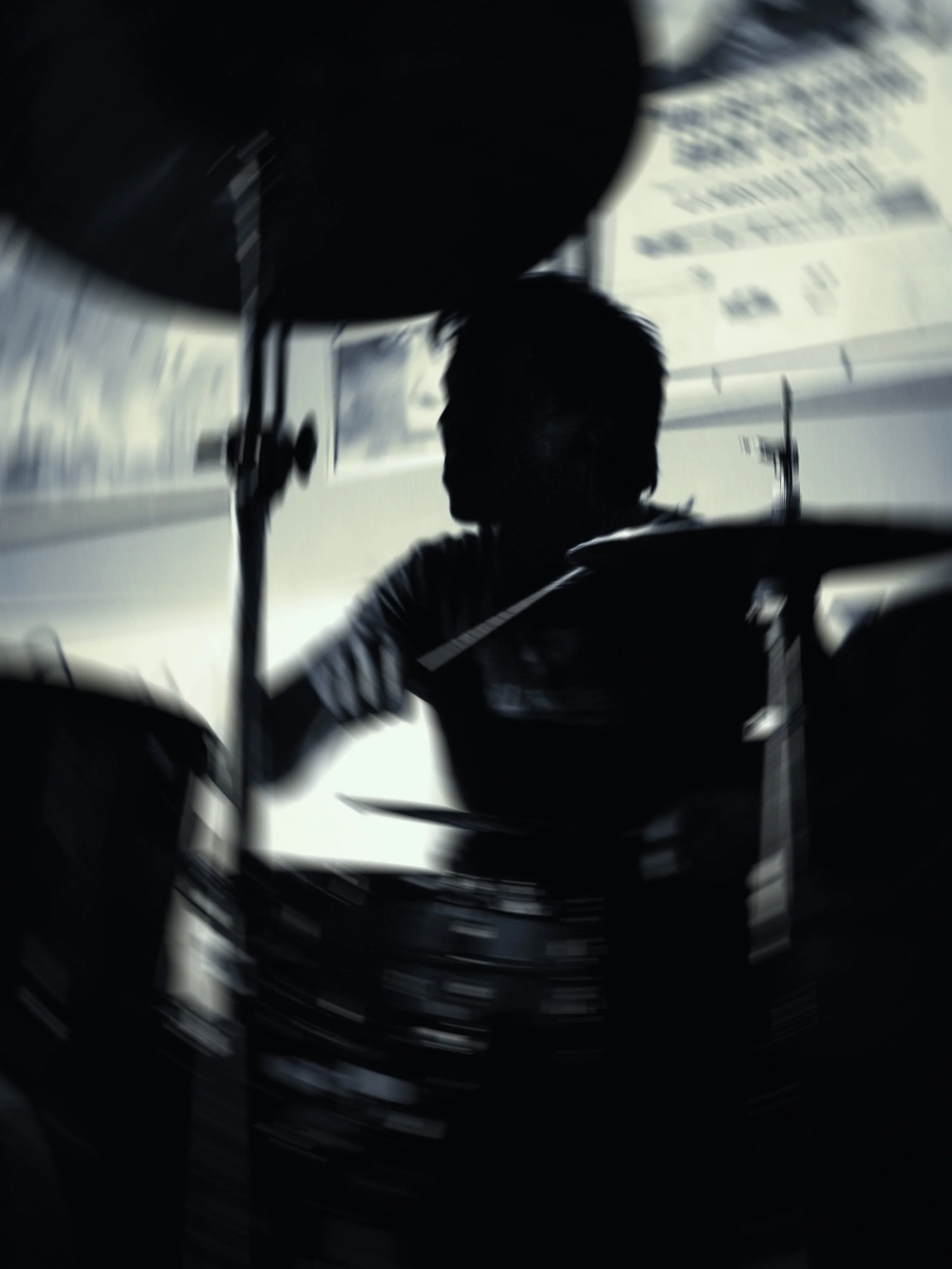 A silhouette of a person sitting in a cockpit with a large, curved window showing an airplane wing and cloudy sky outside.