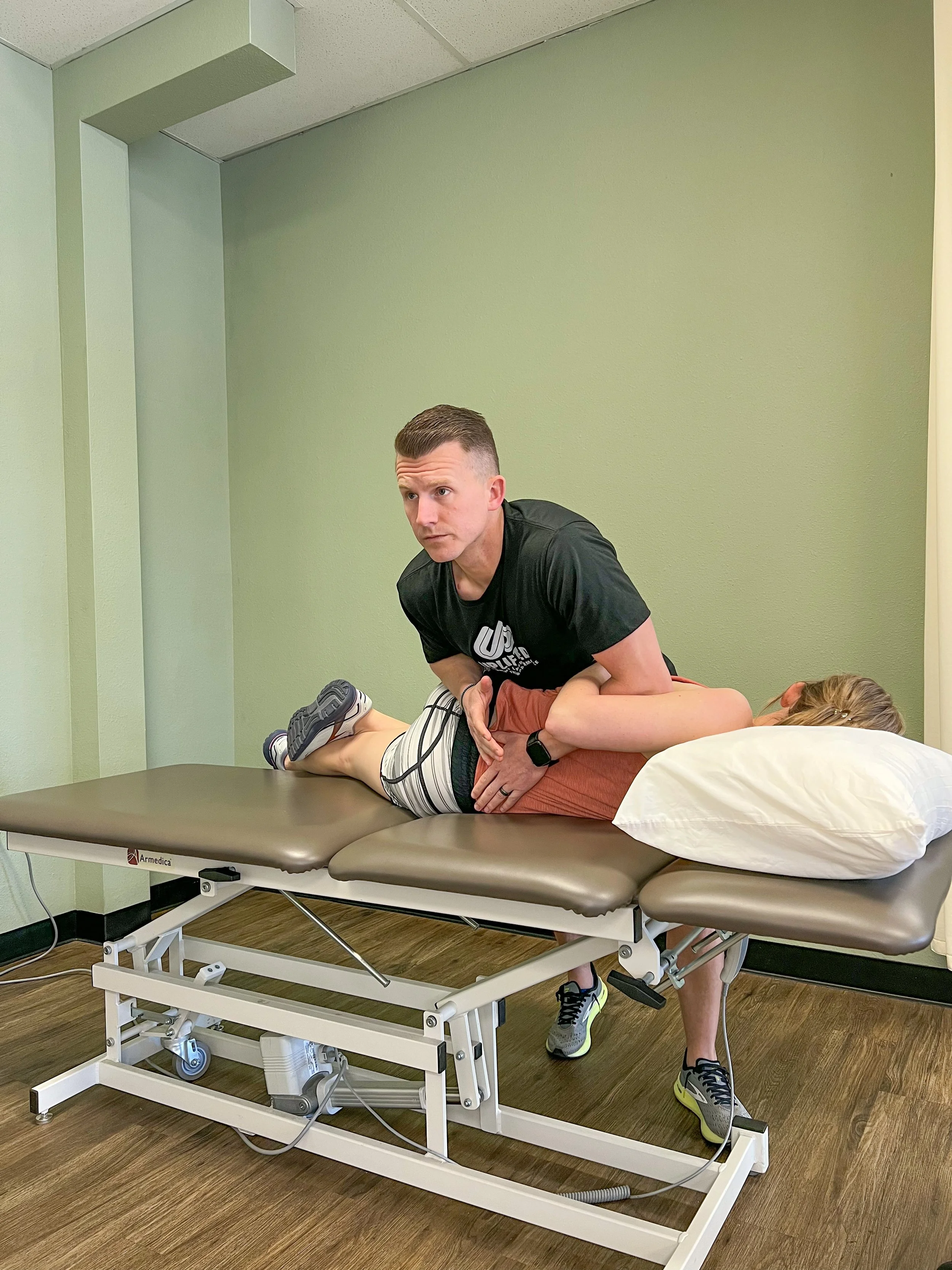 A person lying on a therapy table with a healthcare professional applying manual therapy in a clinical setting.