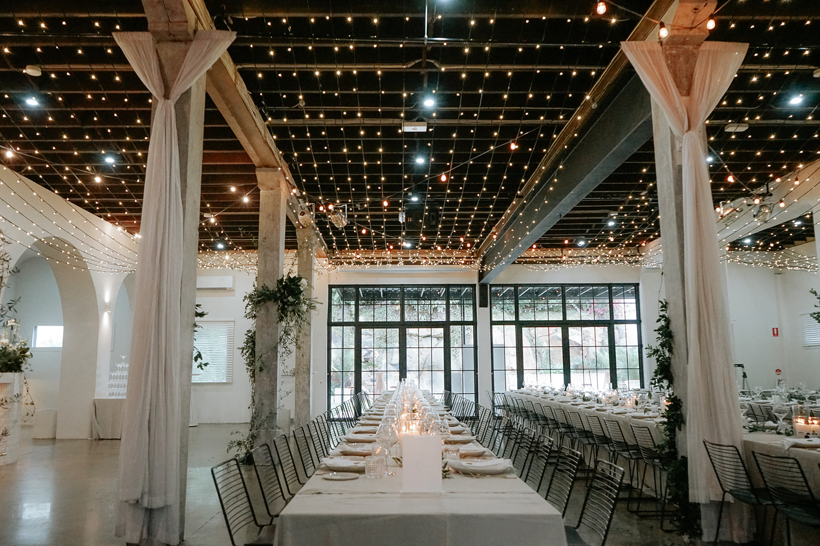 A ceiling of fairy lights over reception tables at The Lussh, a rustic warehouse style venue