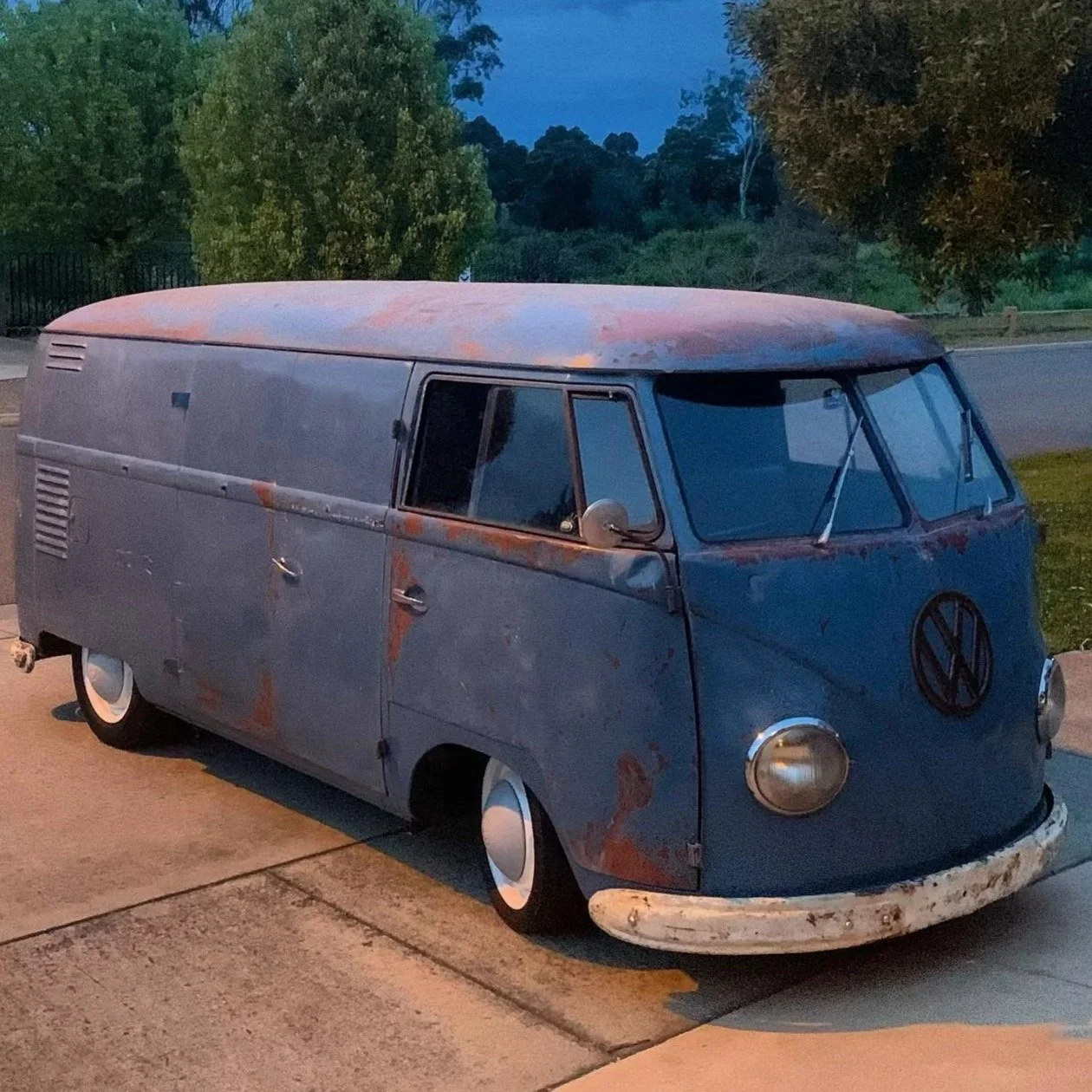 Rusted blue Volkswagen splitwindow kombi parked in a suburban street at twilight