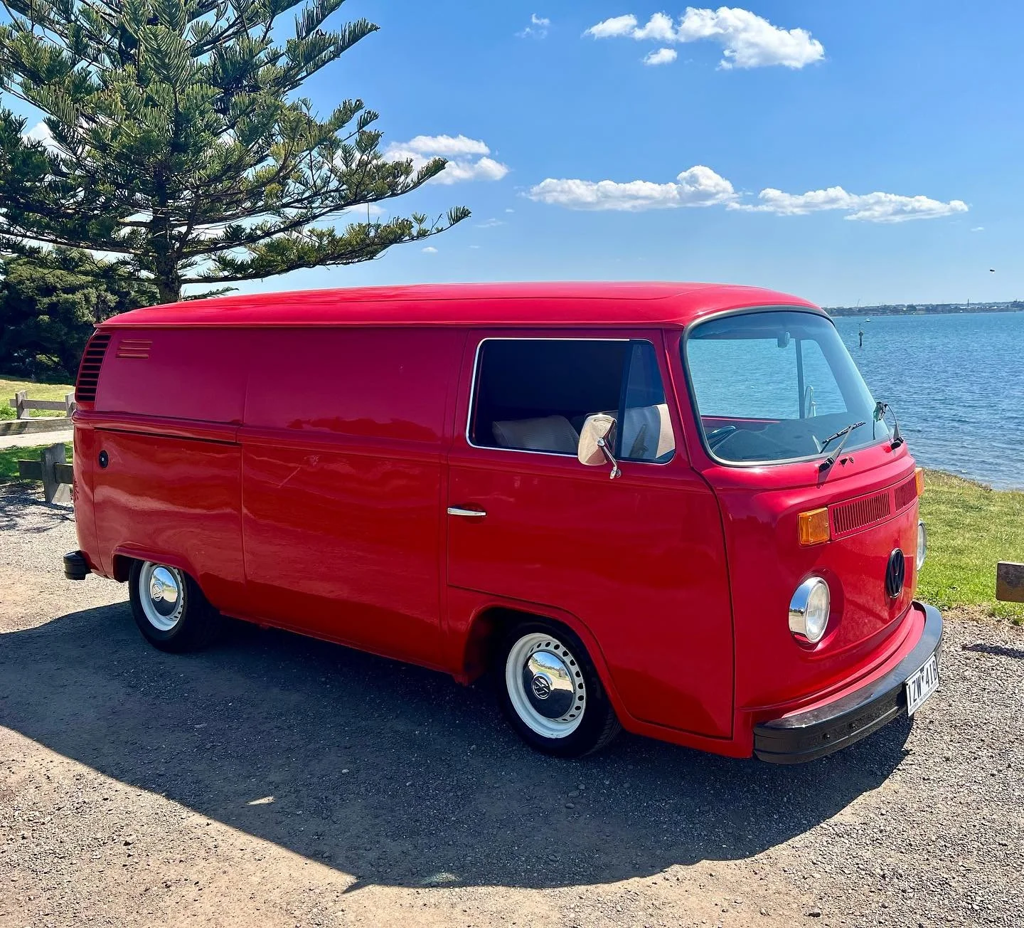 Red volkswagen late bay kombi panel van on the coast
