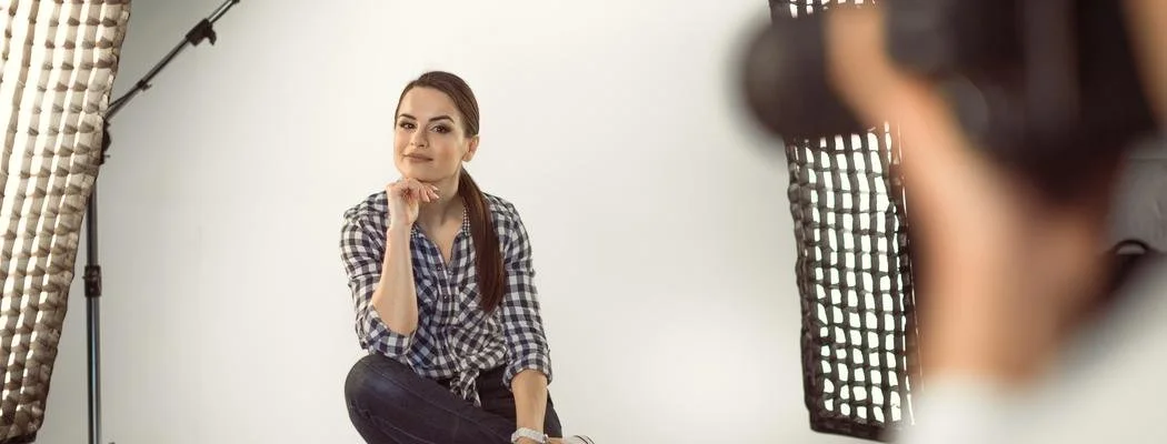 Young woman posing during a photo shoot in a photography studio, with professional lighting equipment visible.