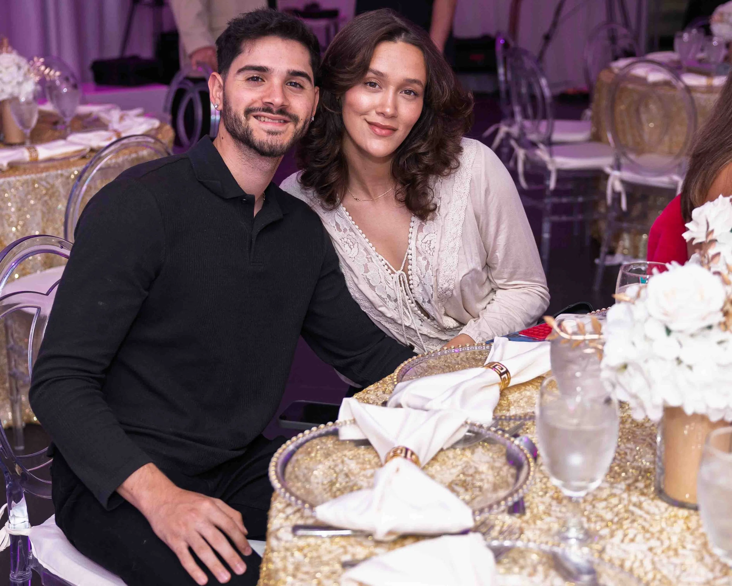 A young man and woman sitting at a decorated banquet table, smiling at the camera.
