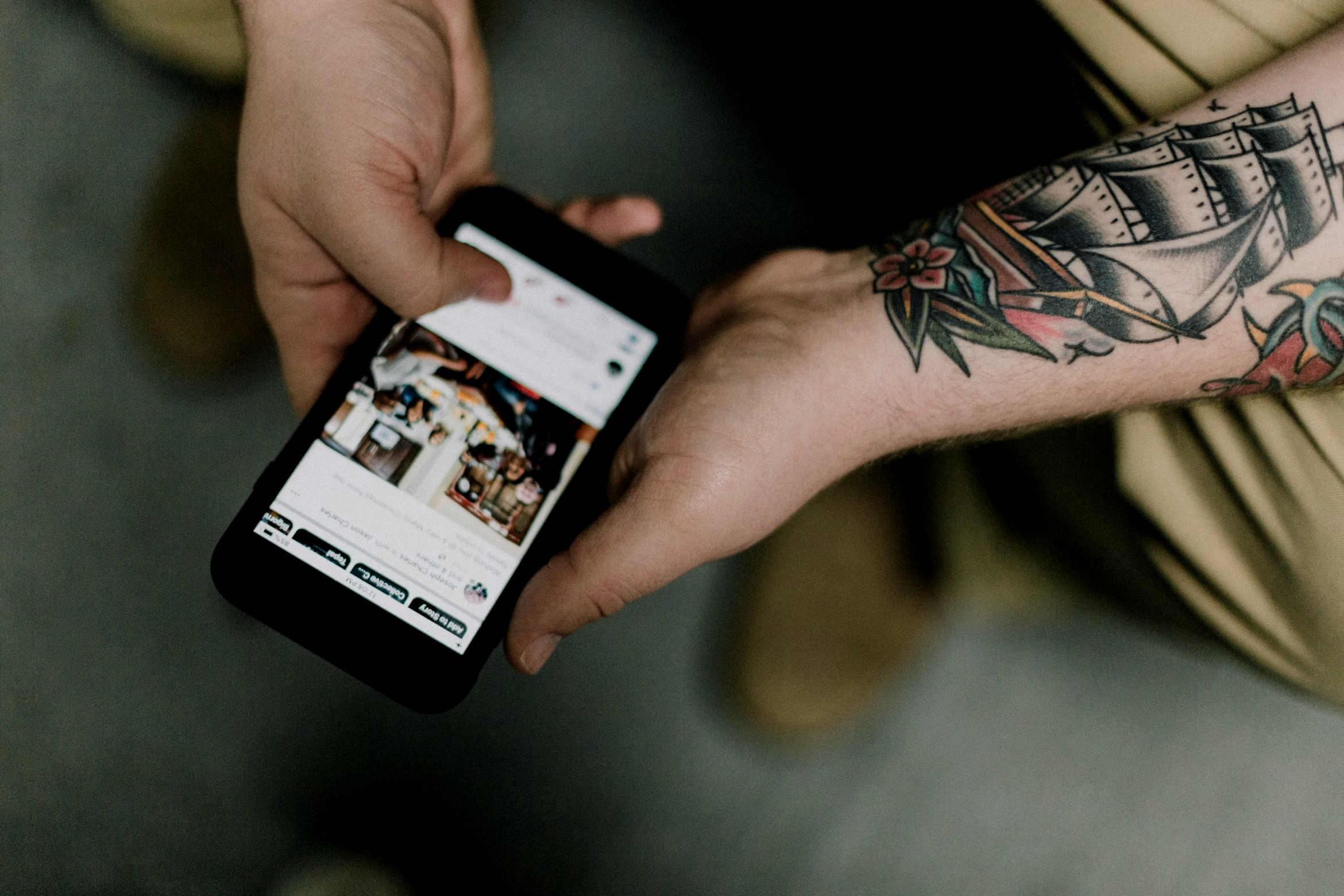 Smartphone on a rustic wooden table with social media app icons on the screen, next to a glass of coffee with a straw.