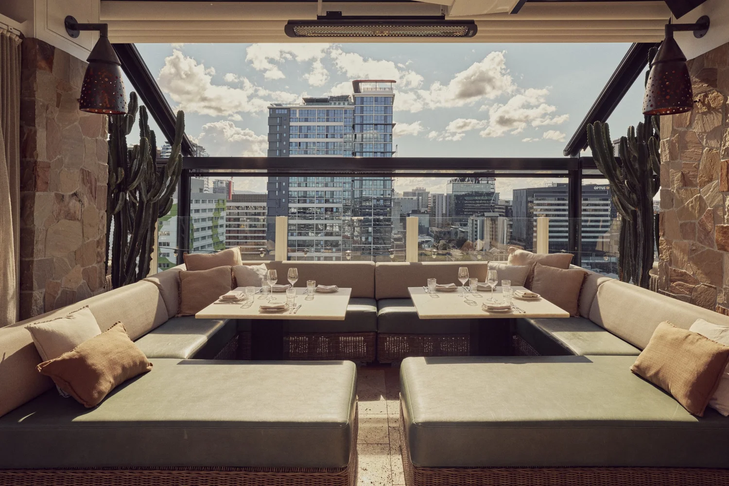 Lounge booth at MAYA with two set tables, stone walls, cacti and city views