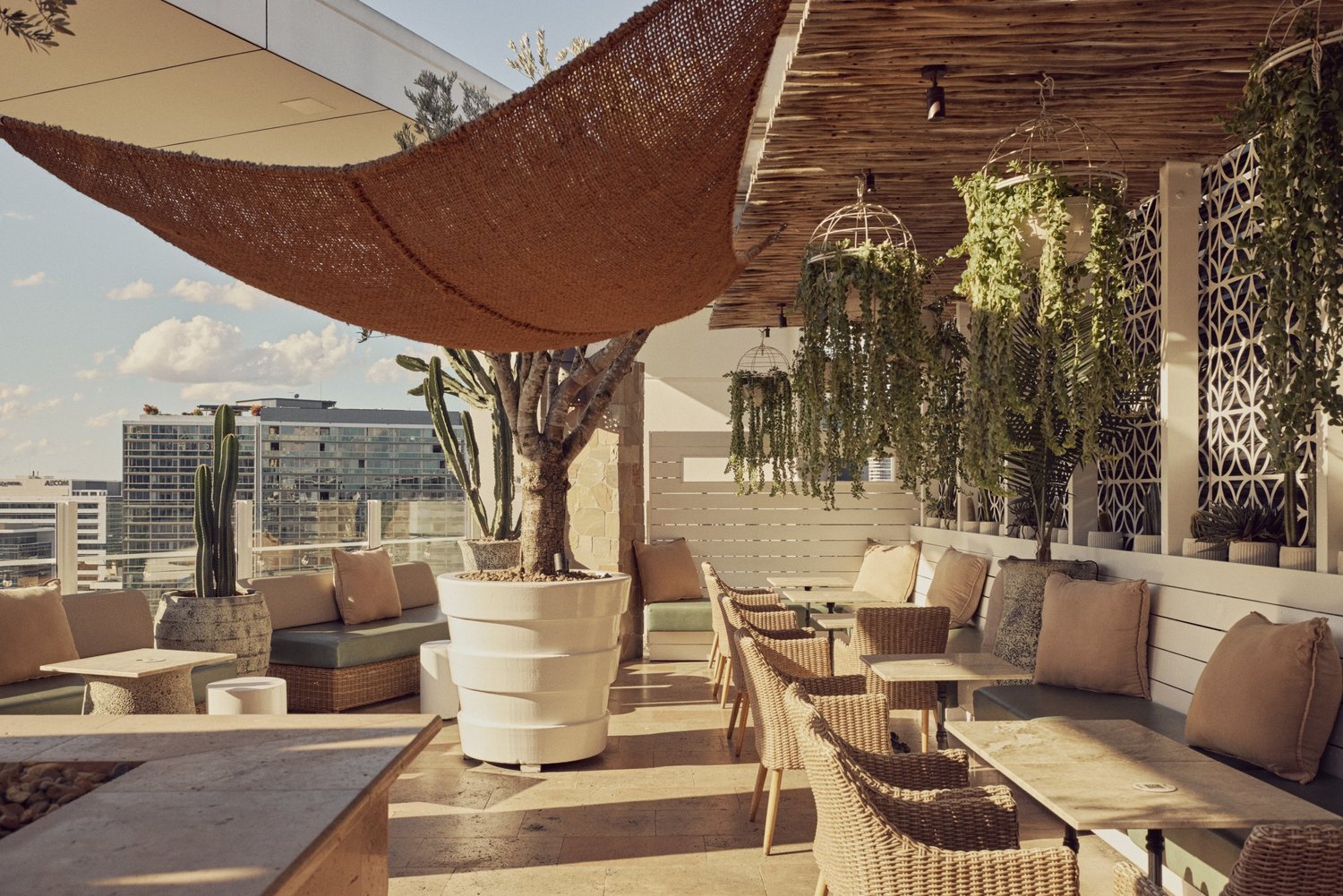 Lounge seating across the MAYA rooftop beneath a woven shade sail