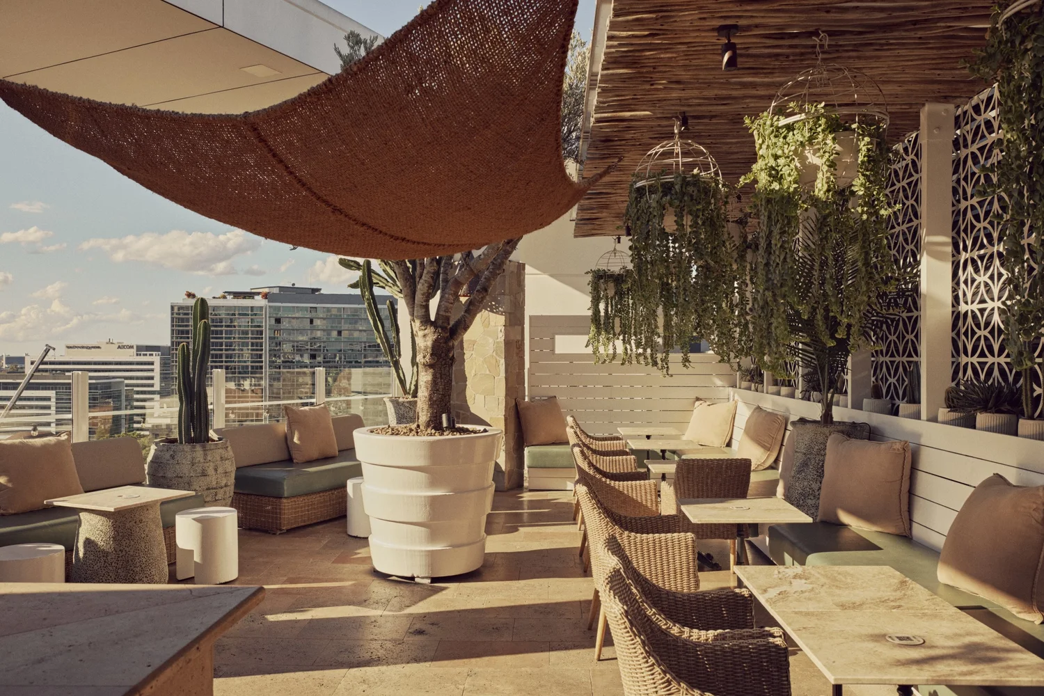 Courtyard lounge seating at MAYA beneath a woven shade sail