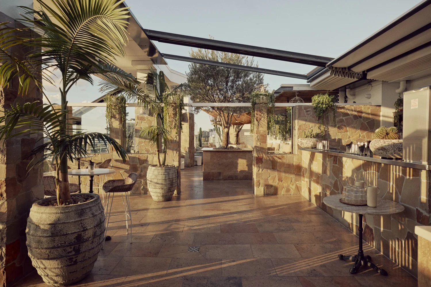 The Patio Bar at MAYA with its stone bar, palms and open sky