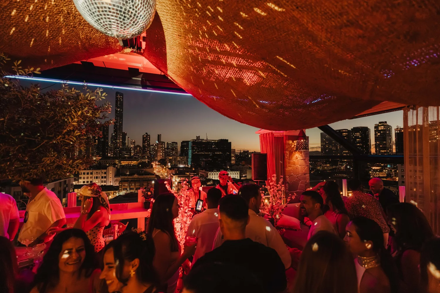 A Christmas party crowd on the MAYA rooftop at night with the city lights behind