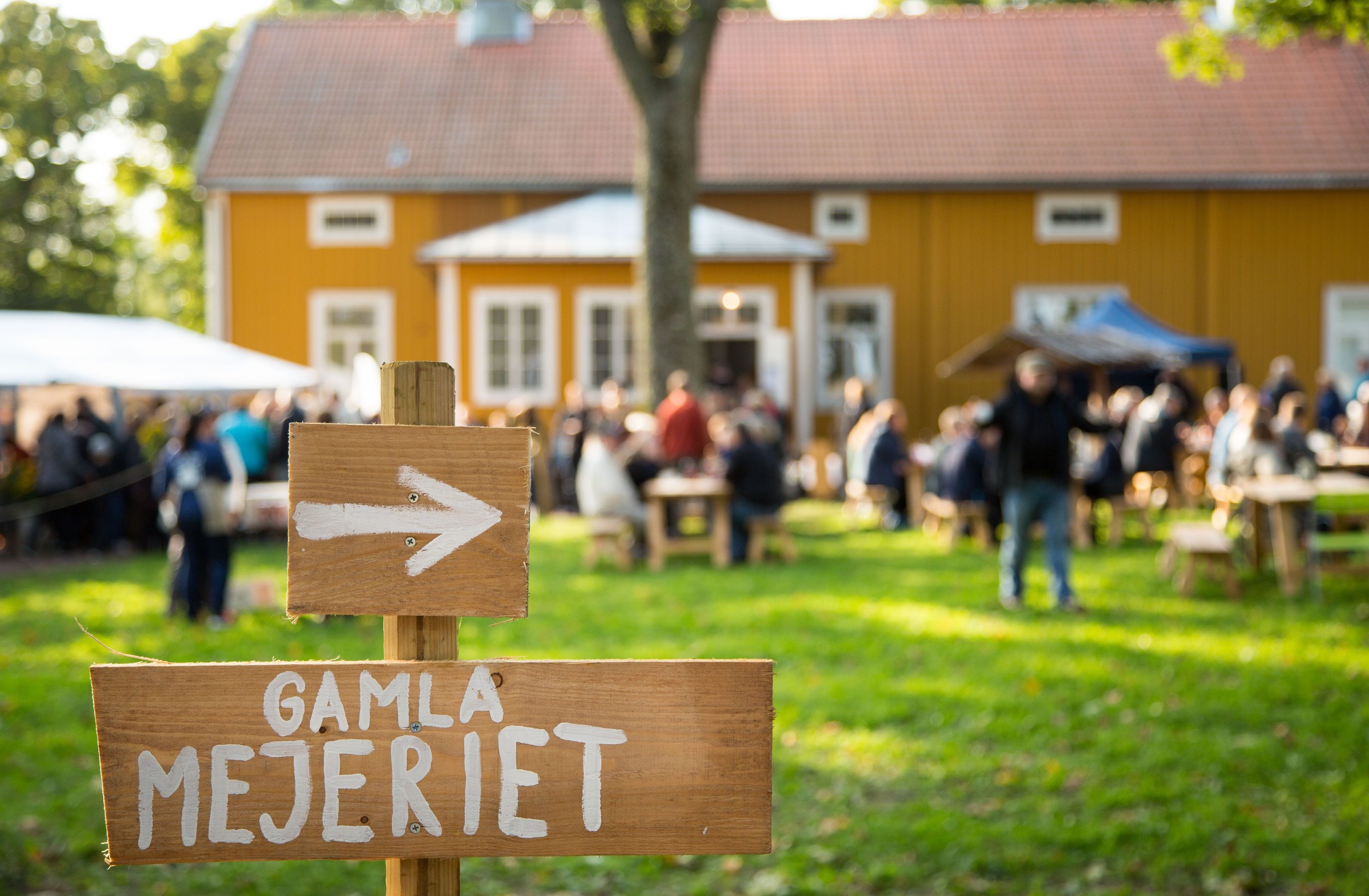 Wooden sign pointing towards a summer event in Åland.