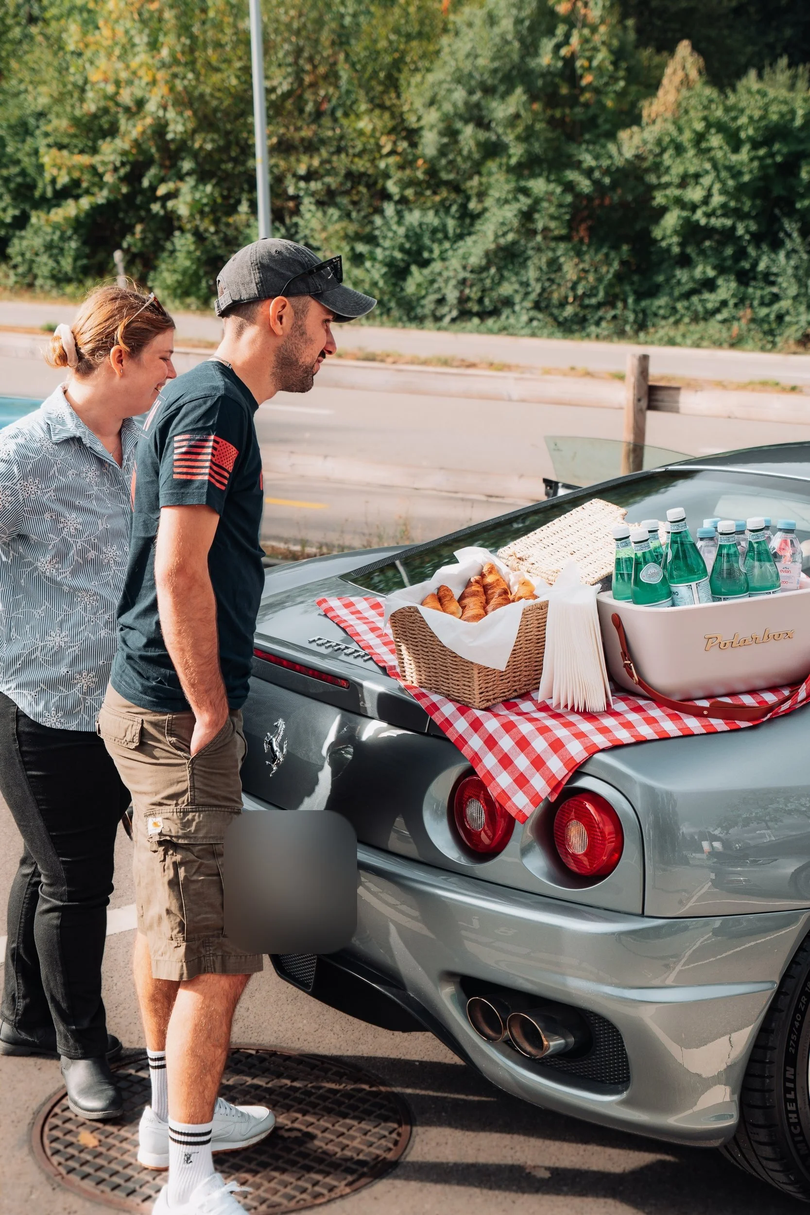 Zwei Fahrer bei einem Picknickhalt, Snacks auf dem Heck eines silbernen Ferrari 360, One Tank Tour