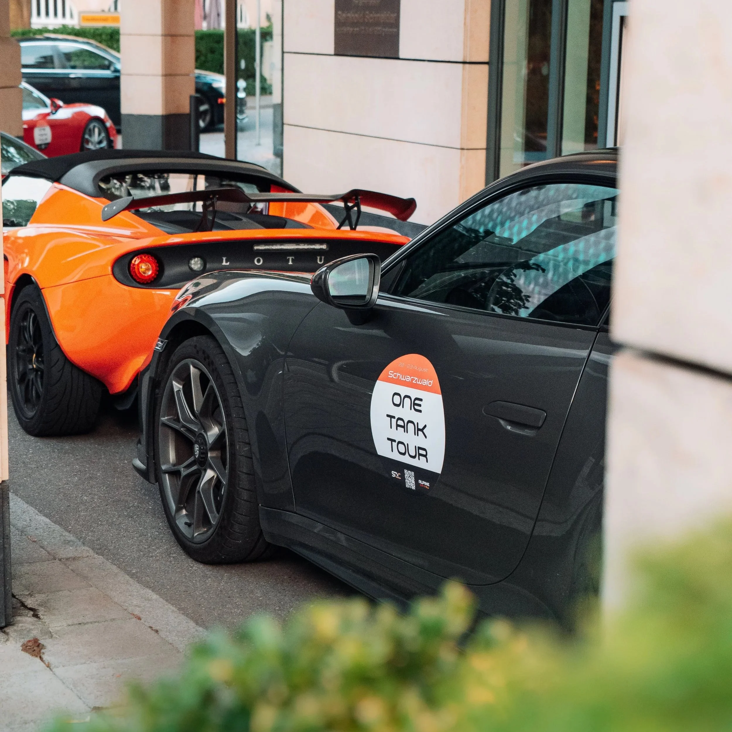 Lotus Elise und Porsche mit One Tank Tour Badges vor dem Hotel, One Tank Tour Schwarzwald 2026