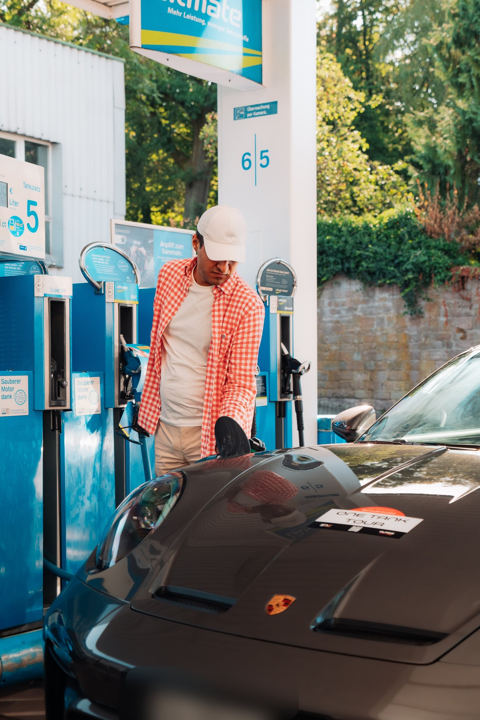 Fahrer tankt einen schwarzen Porsche bei einem Tankstopp auf einer früheren One Tank Tour
