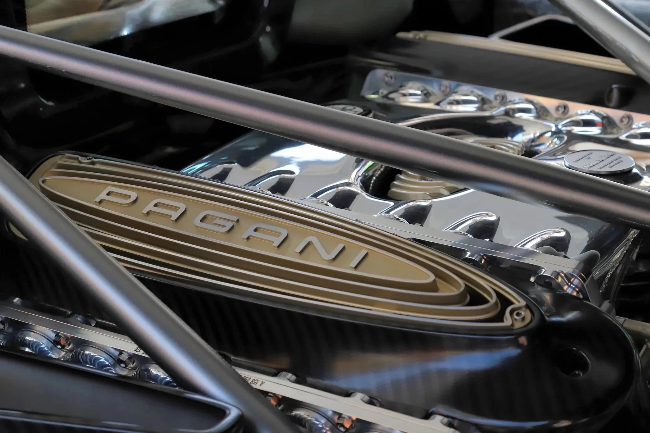Close-up of a car engine with a prominent gold-colored Porsche badge on the engine cover.